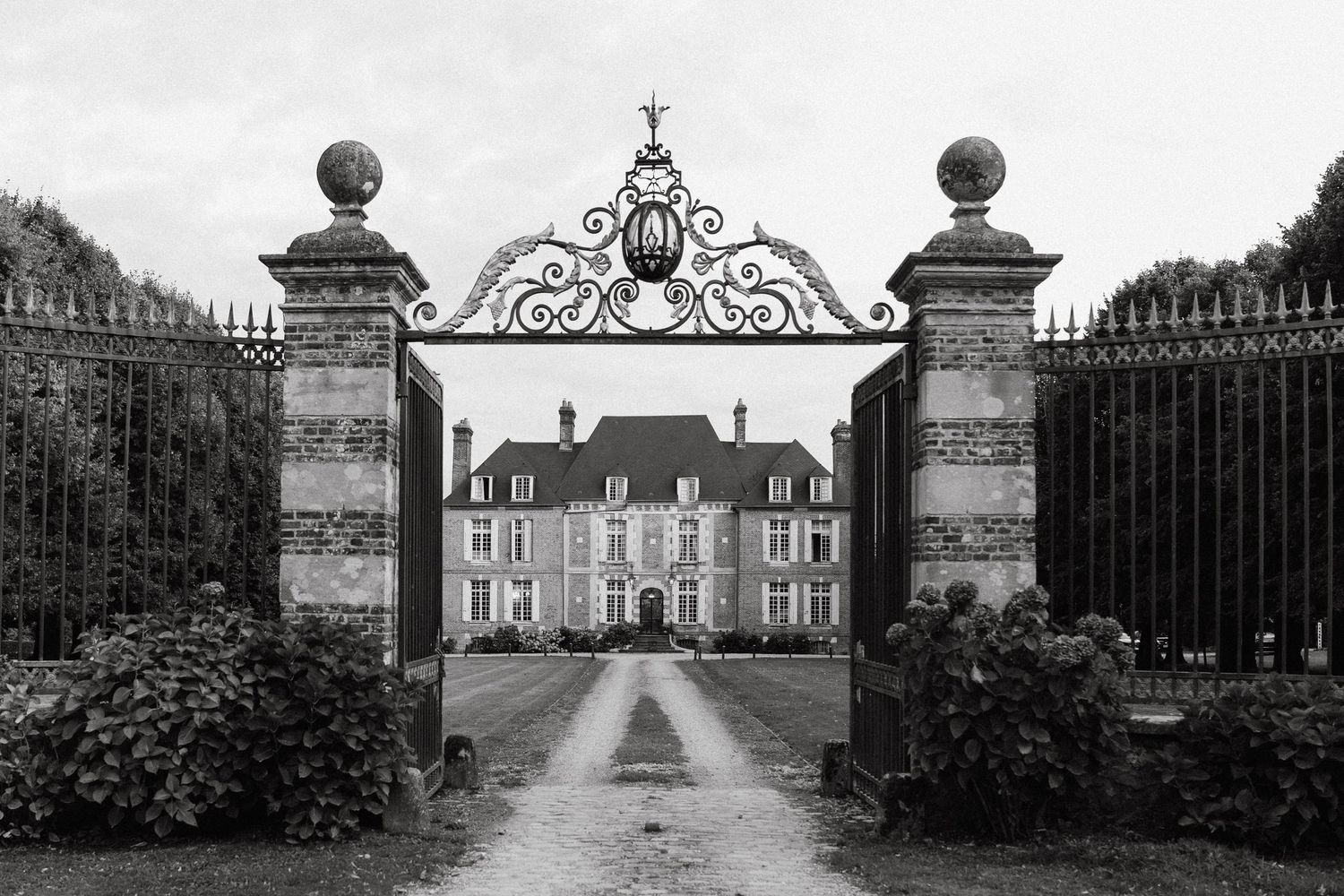 Grand entrance gates and driveway leading to a majestic French chateau.