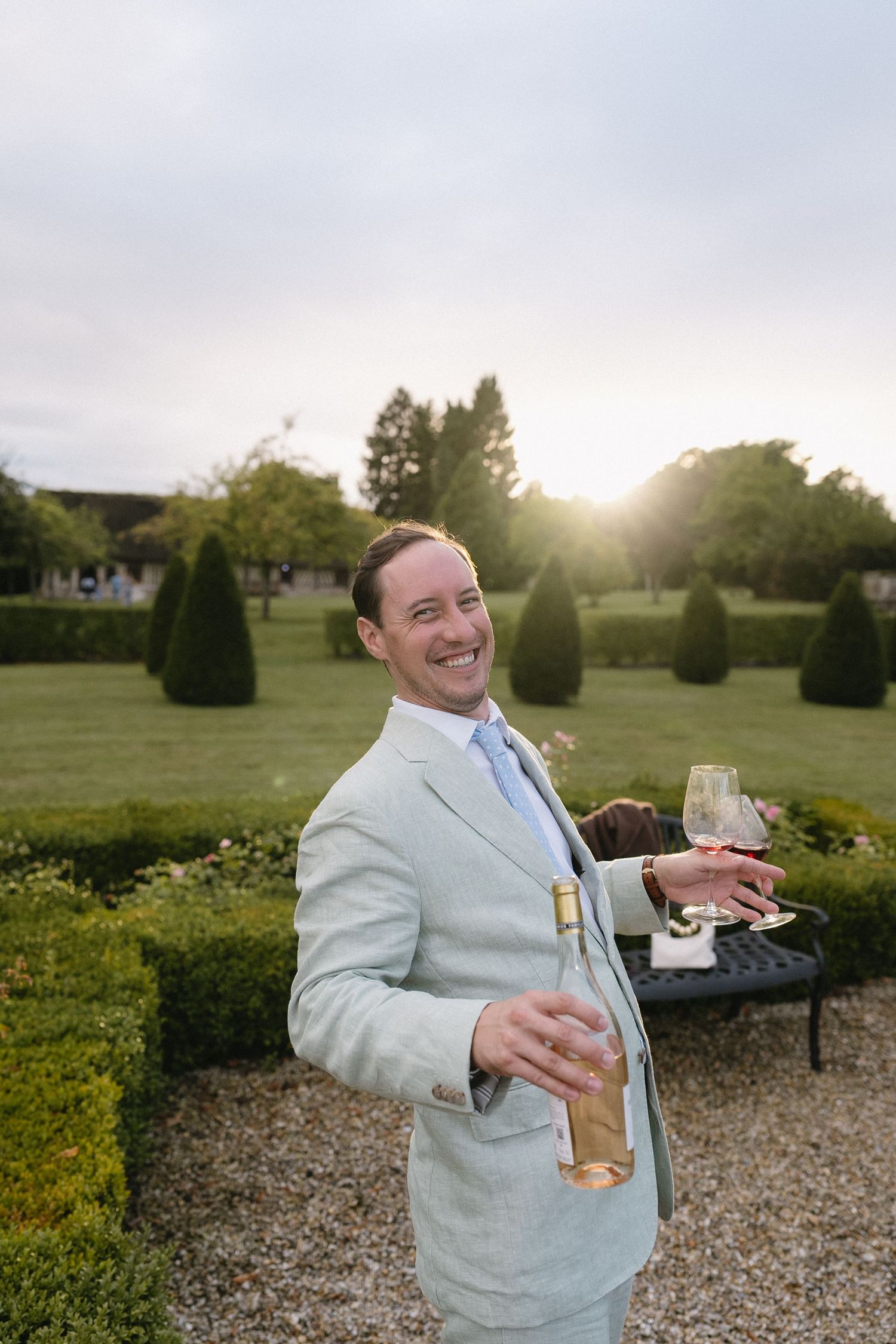 A sequence of outdoor photos showing someone in a light colored suit holding a drink at a garden event.