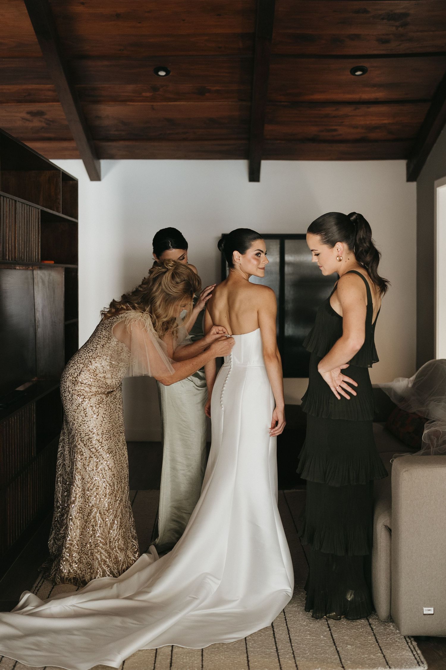 Wedding preparation scene with flowing white dress being adjusted.