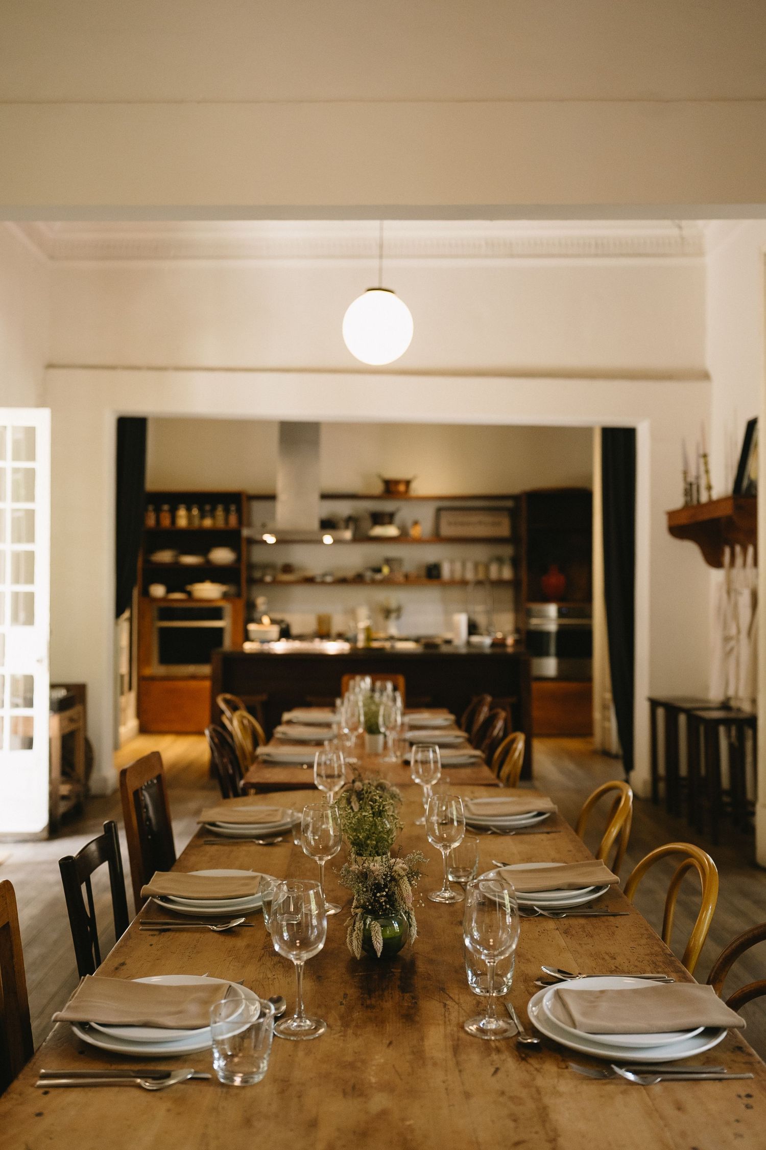 Long wooden dining table set with elegant place settings and glassware.