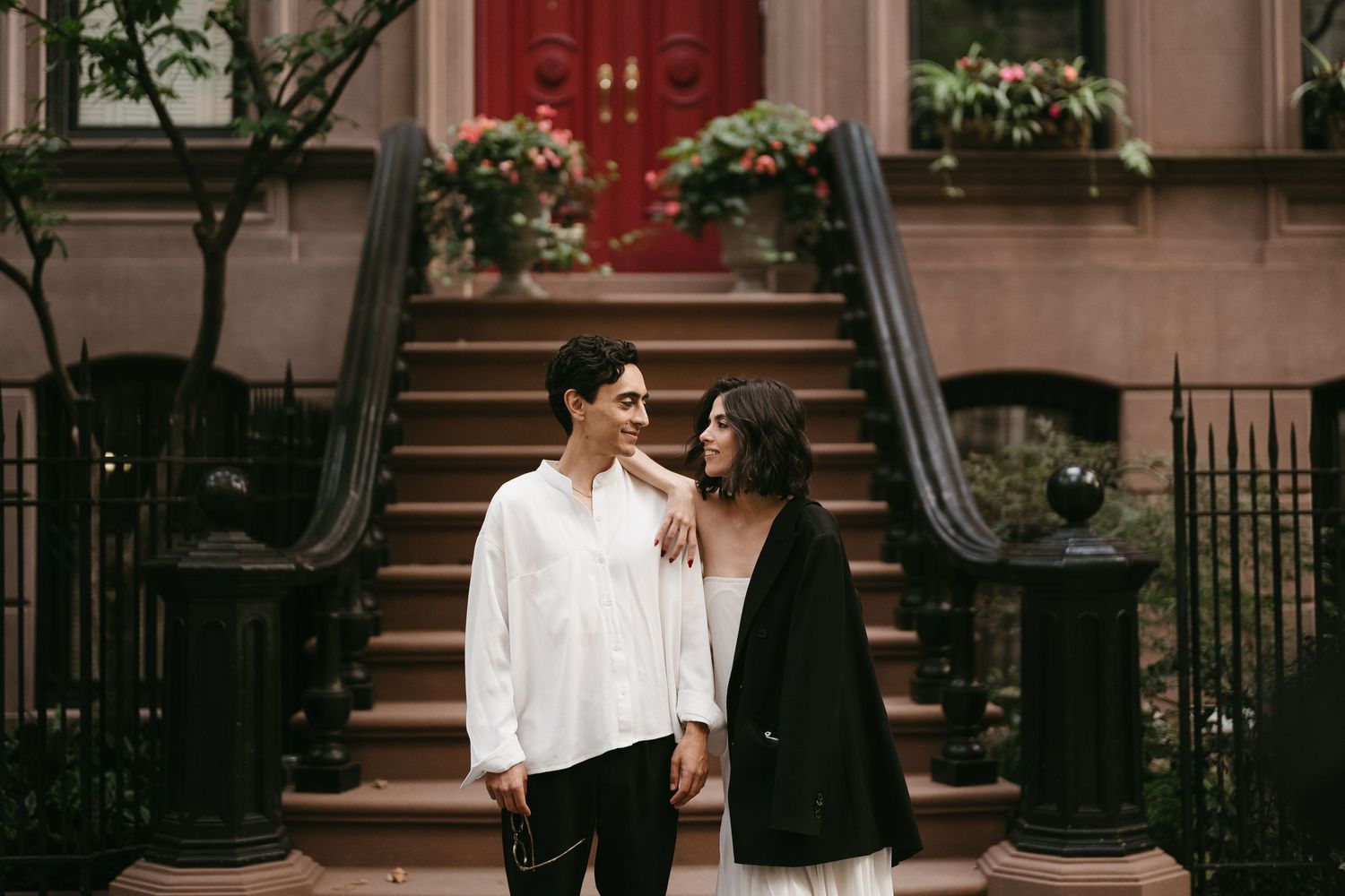 People standing near brownstone steps with decorative railings.