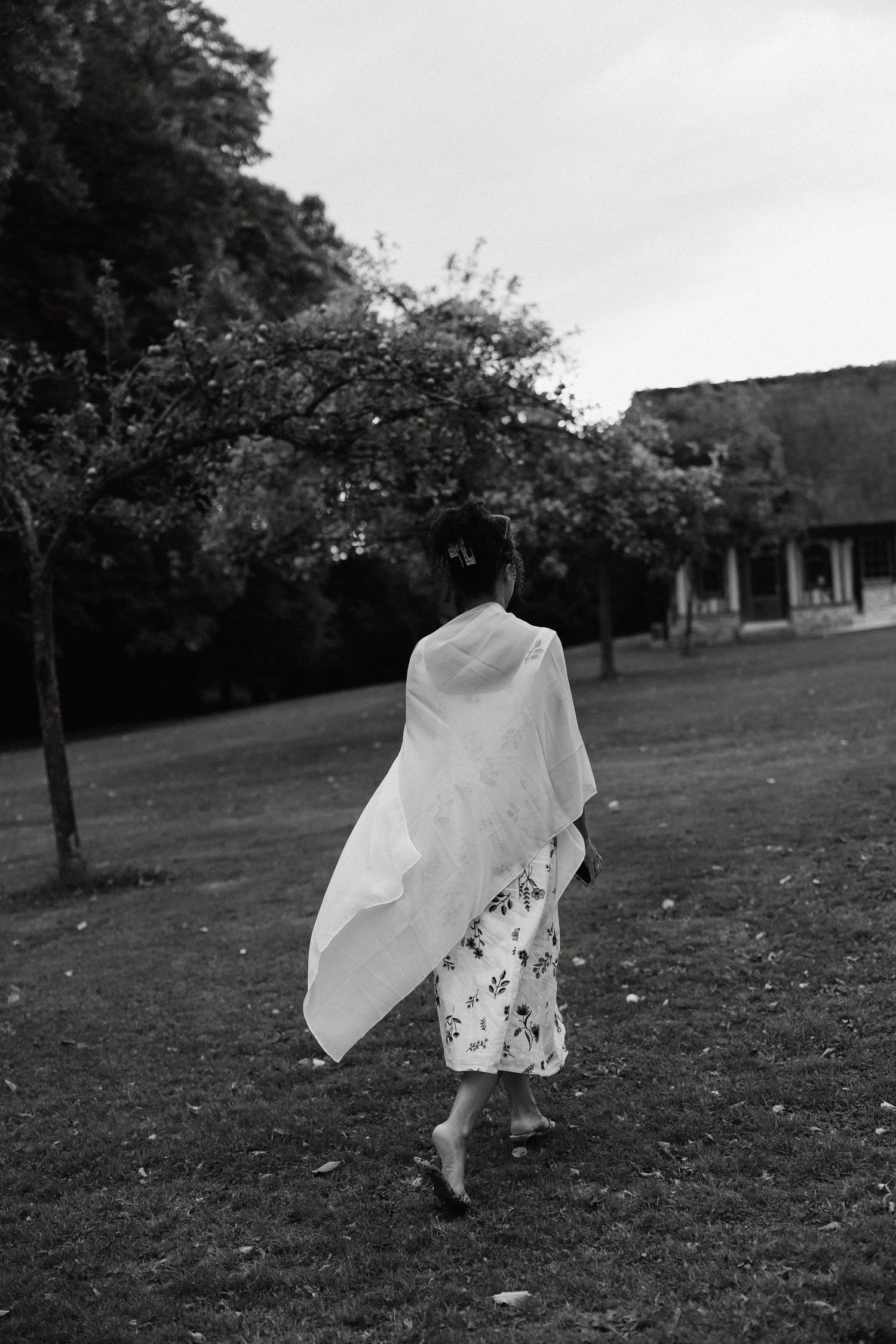 A sequence of black and white photos showing a figure in white fabric dancing and twirling in a grassy field.