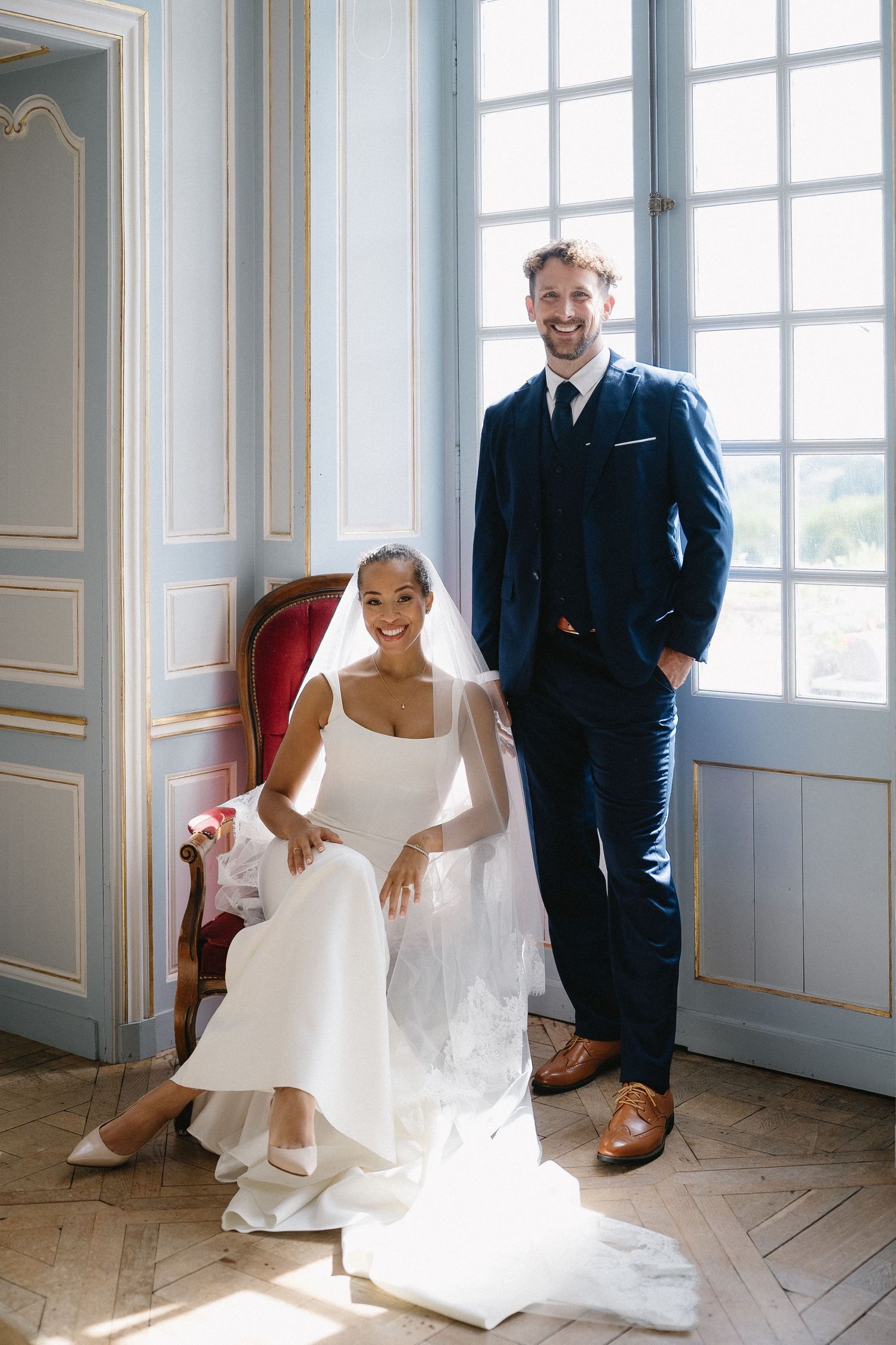 Elegant wedding portraits in a bright room with large windows and classic architectural details.