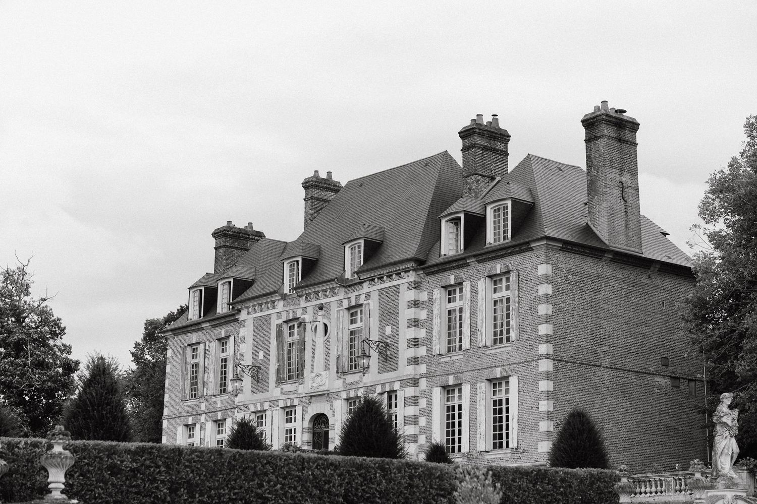 Historic French chateau-style mansion with white stone walls and dormer windows shown in a black and white photograph.
