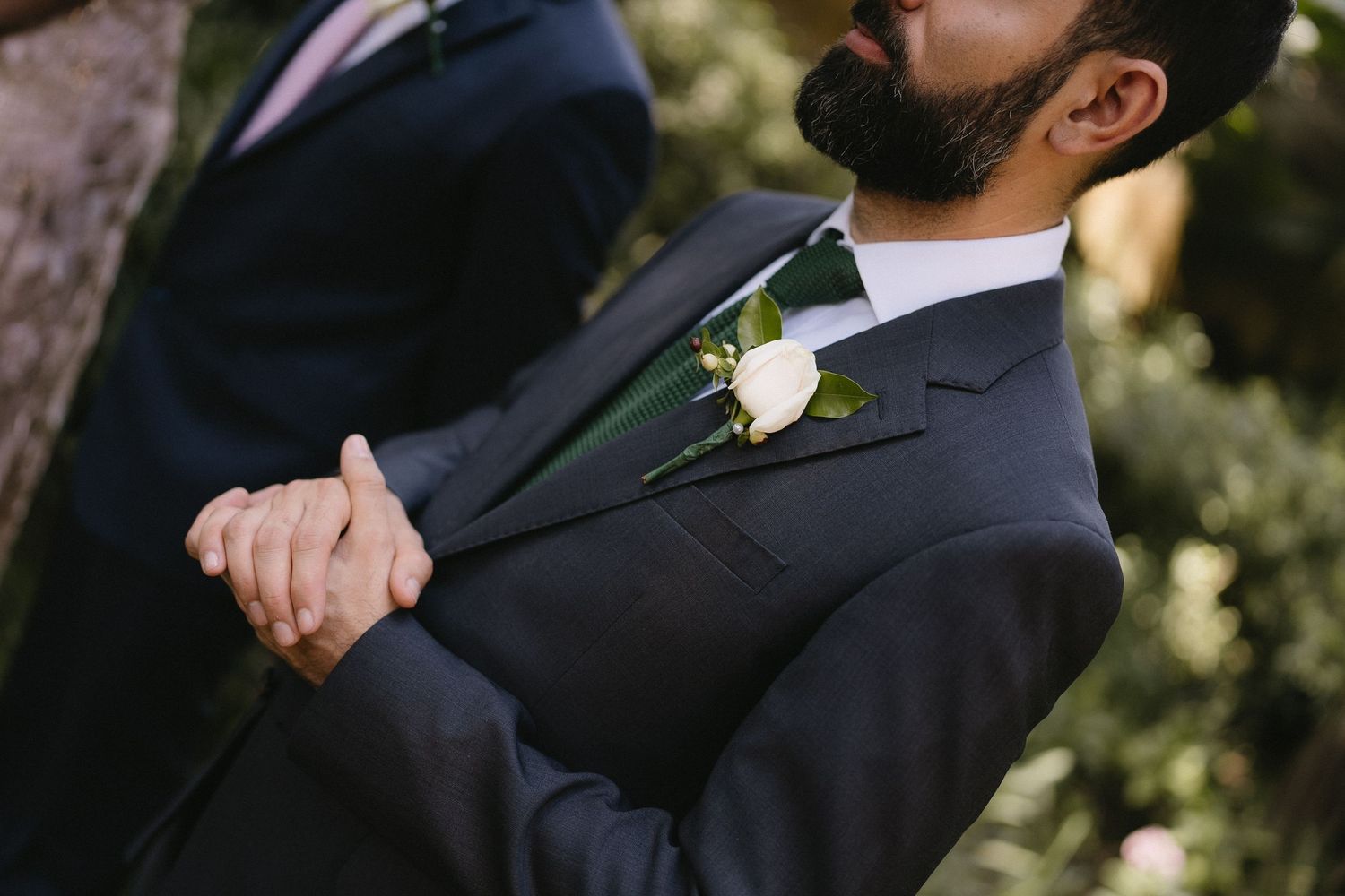 Wedding guests in formal attire gathered at an outdoor ceremony.