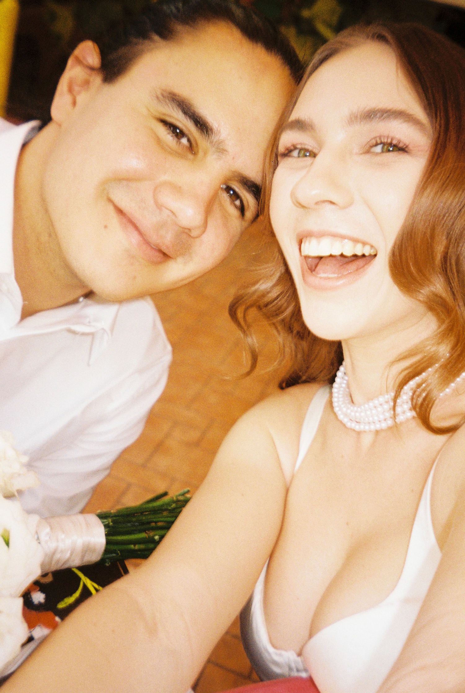 Close-up portrait of a couple sharing joyful laughter against a warm background.