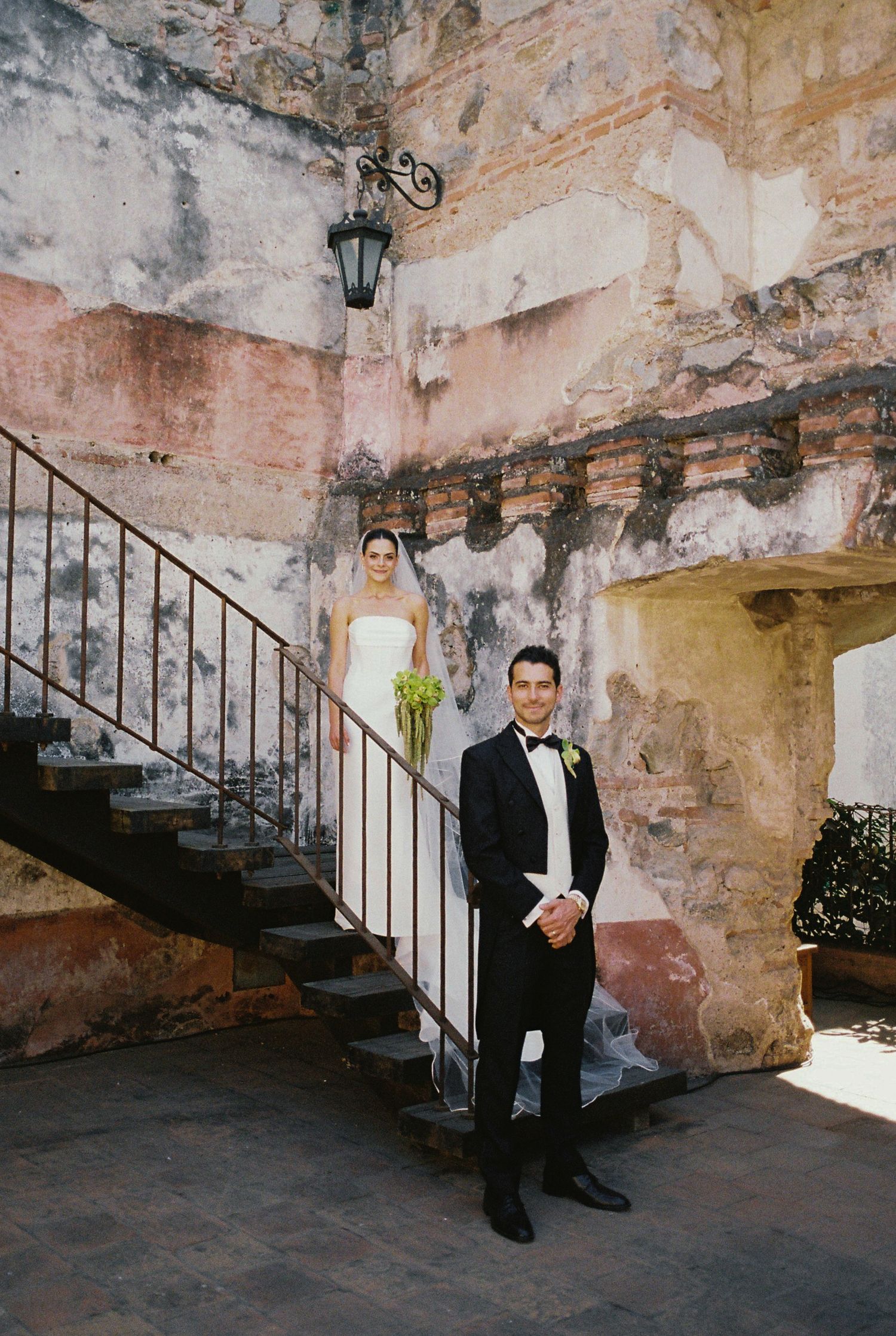 A series of formal portraits taken against weathered stone walls and iron railings.