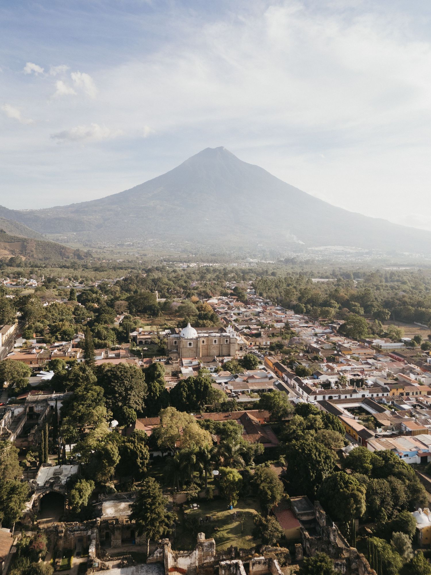 Scenic cityscape view with a majestic volcano mountain rising in the background against a cloudy sky.