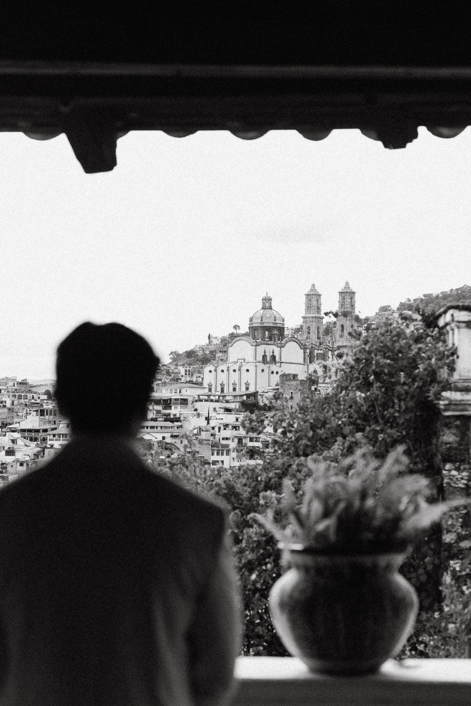 A black and white cityscape view of Rome with silhouetted figures in the foreground looking out at historic buildings and domes.