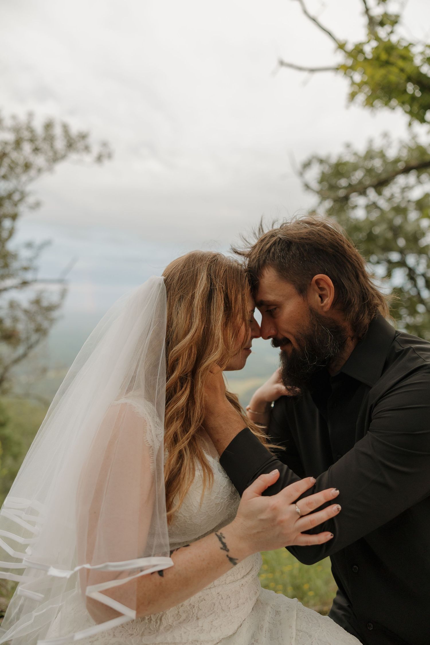 An intimate moment between a couple captured against a misty mountain backdrop.