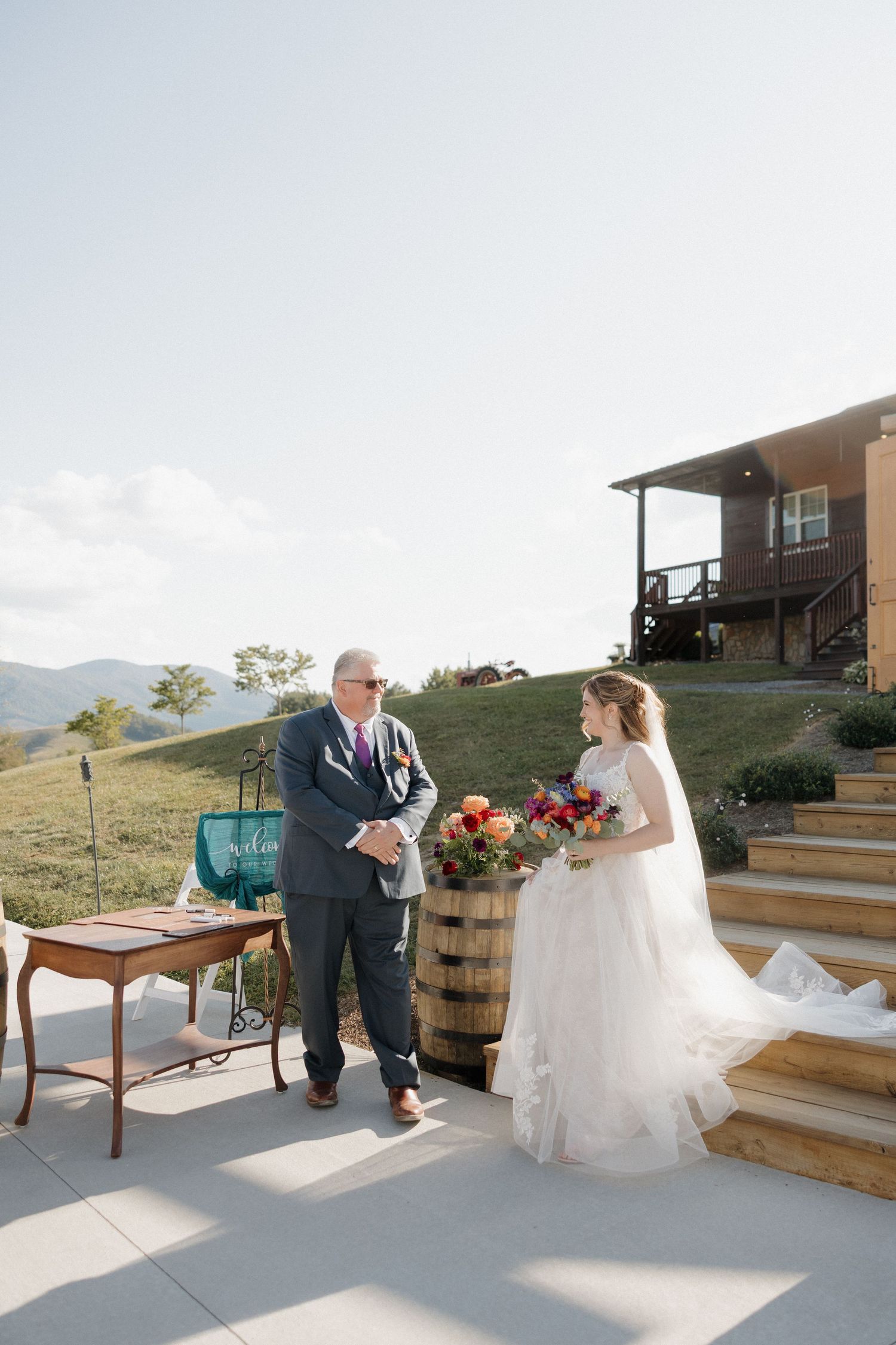 Rustic outdoor wedding setup with wooden barrels and steps against mountain backdrop.