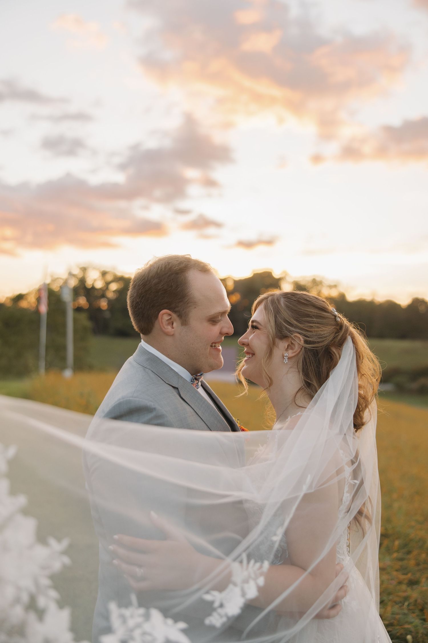 Romantic sunset portrait with flowing veil in golden field.