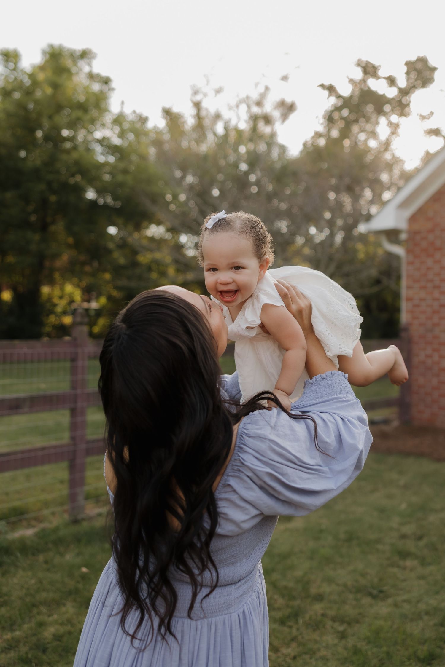 A joyful moment captured in a backyard setting at sunset with natural golden light filtering through trees.