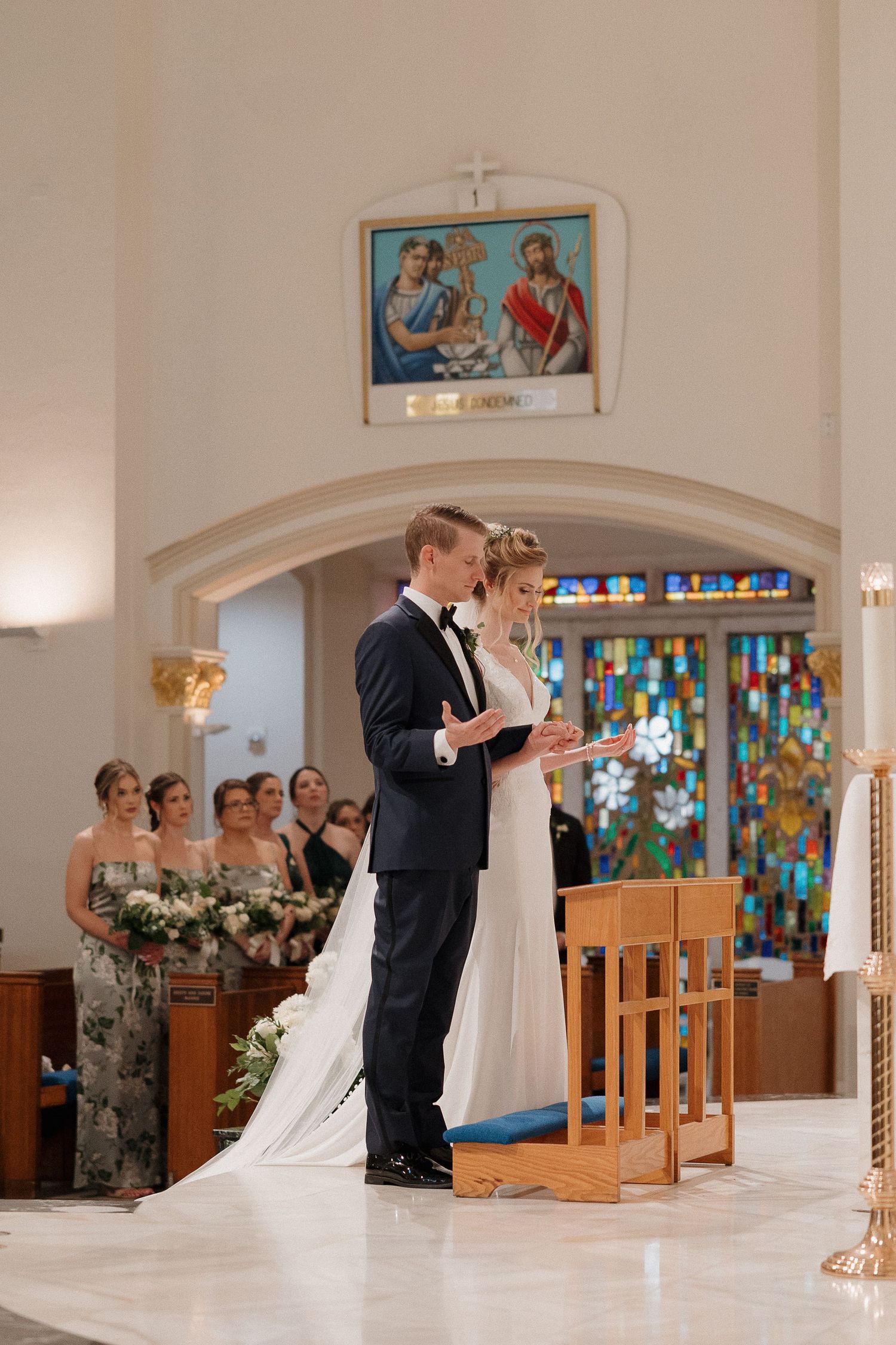 A wedding ceremony in a church sanctuary with stained glass windows and wooden pews.