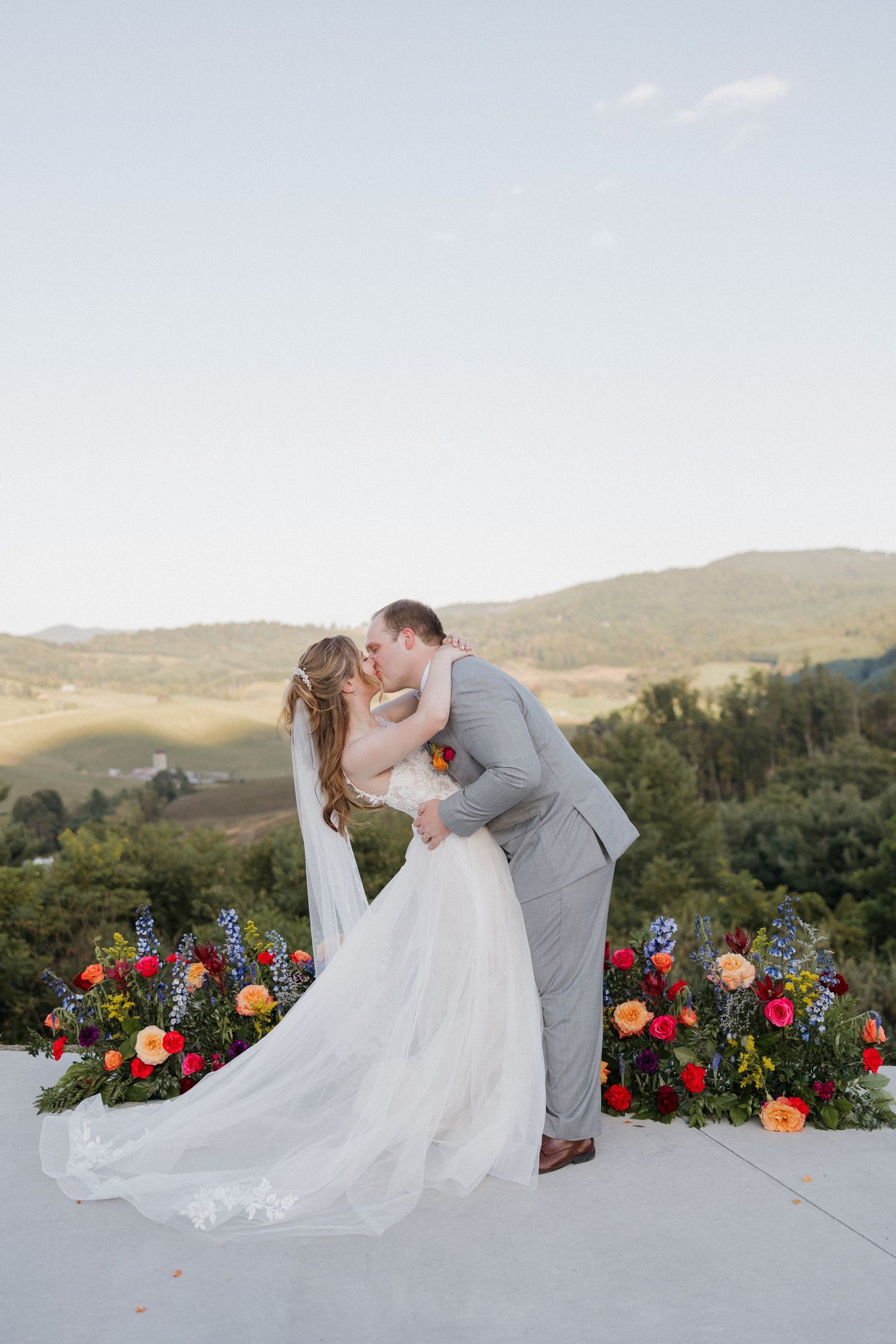 Romantic wedding moment on a terrace decorated with vibrant red and orange flowers.