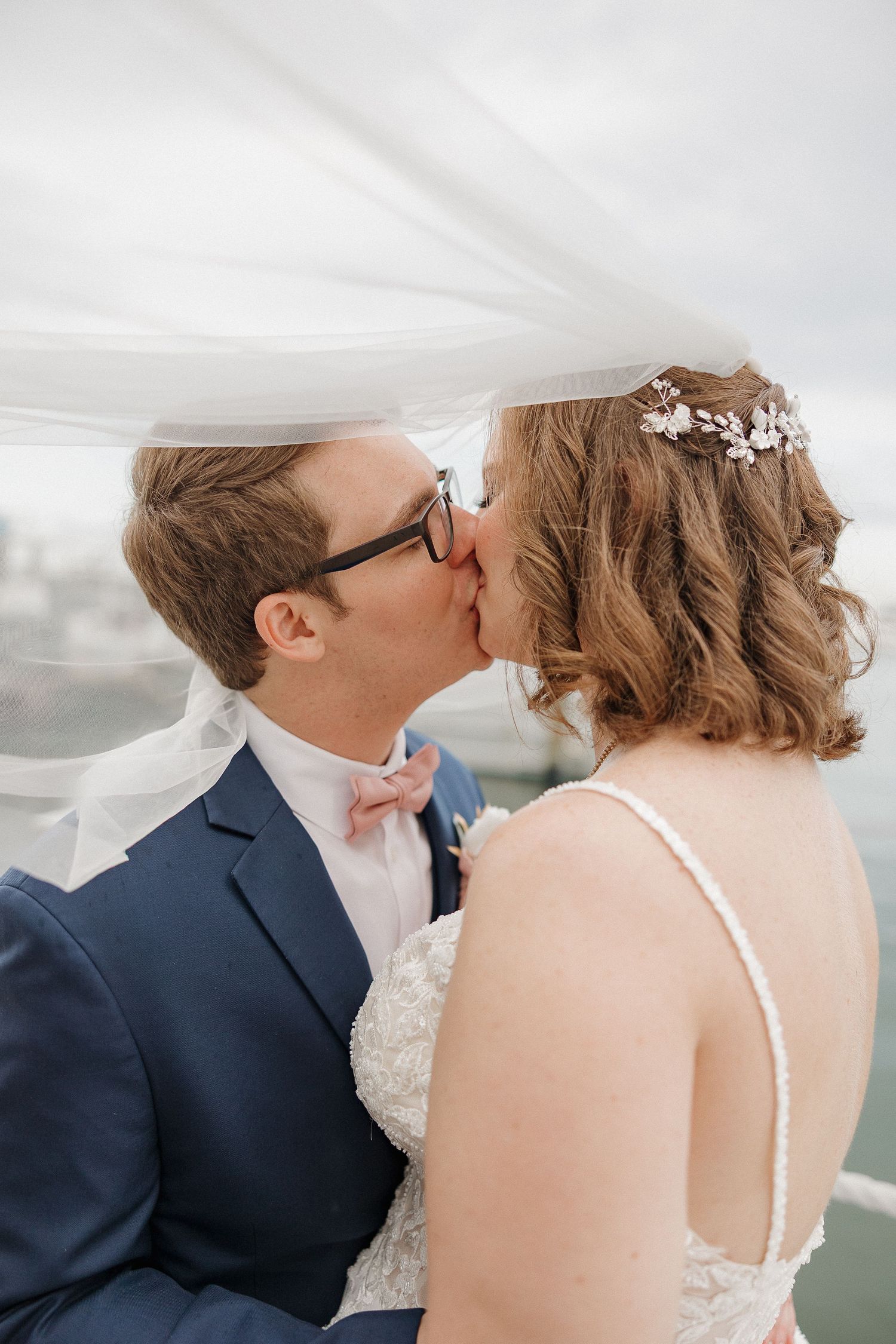 Romantic wedding couple sharing intimate moment on waterfront deck.