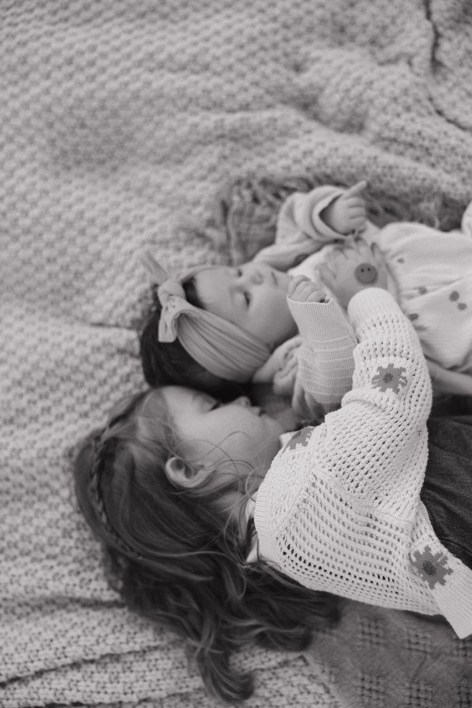 A series of black and white photos showing a child in a white crochet dress lying on a textured blanket.