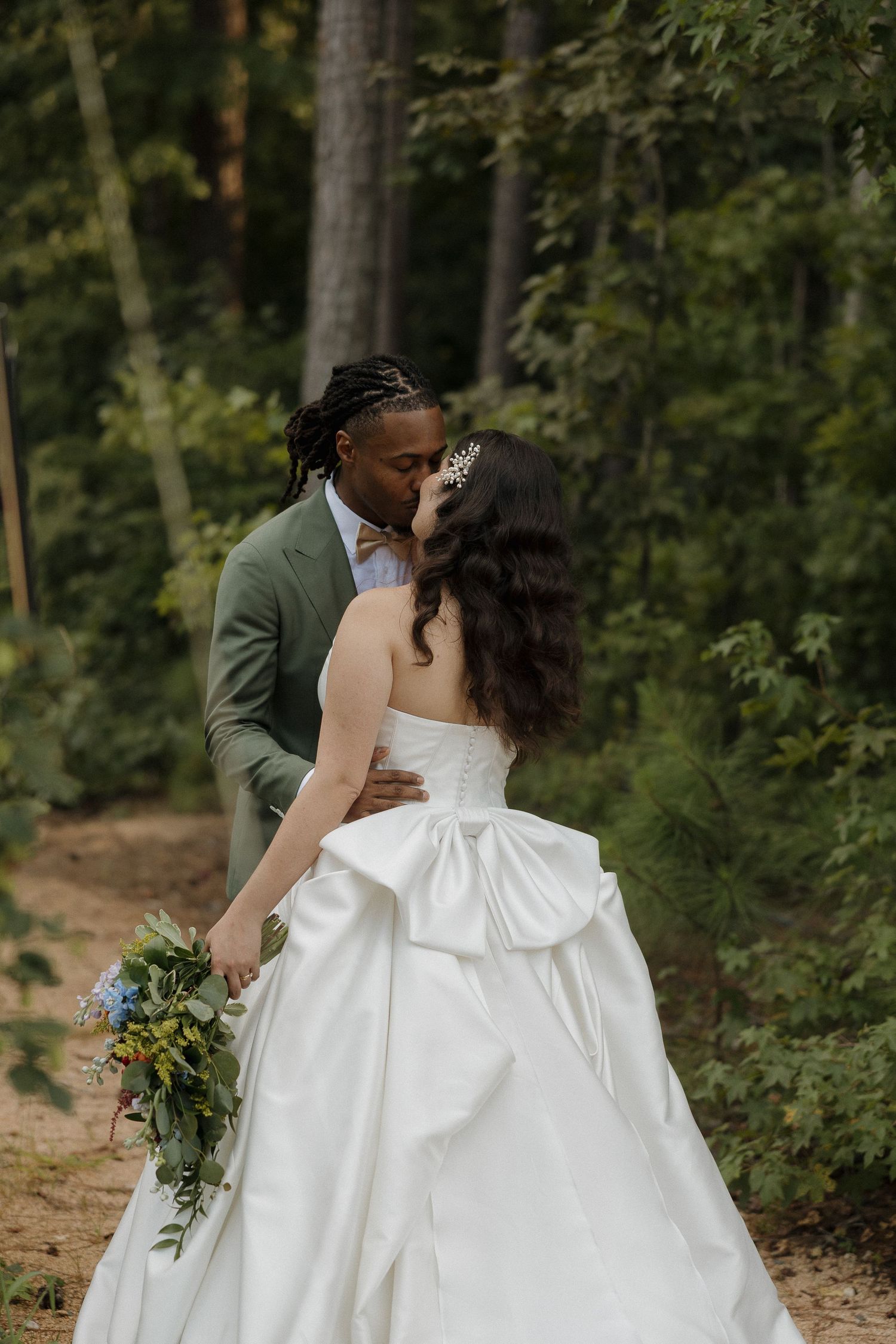 A tender wedding portrait showing a couple in an elegant embrace against a forest backdrop.