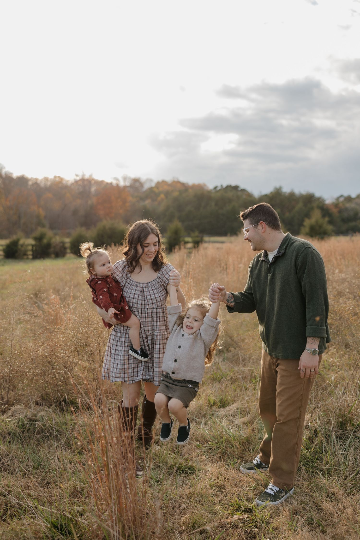 A family enjoys playful moments together in a golden autumn field during sunset.