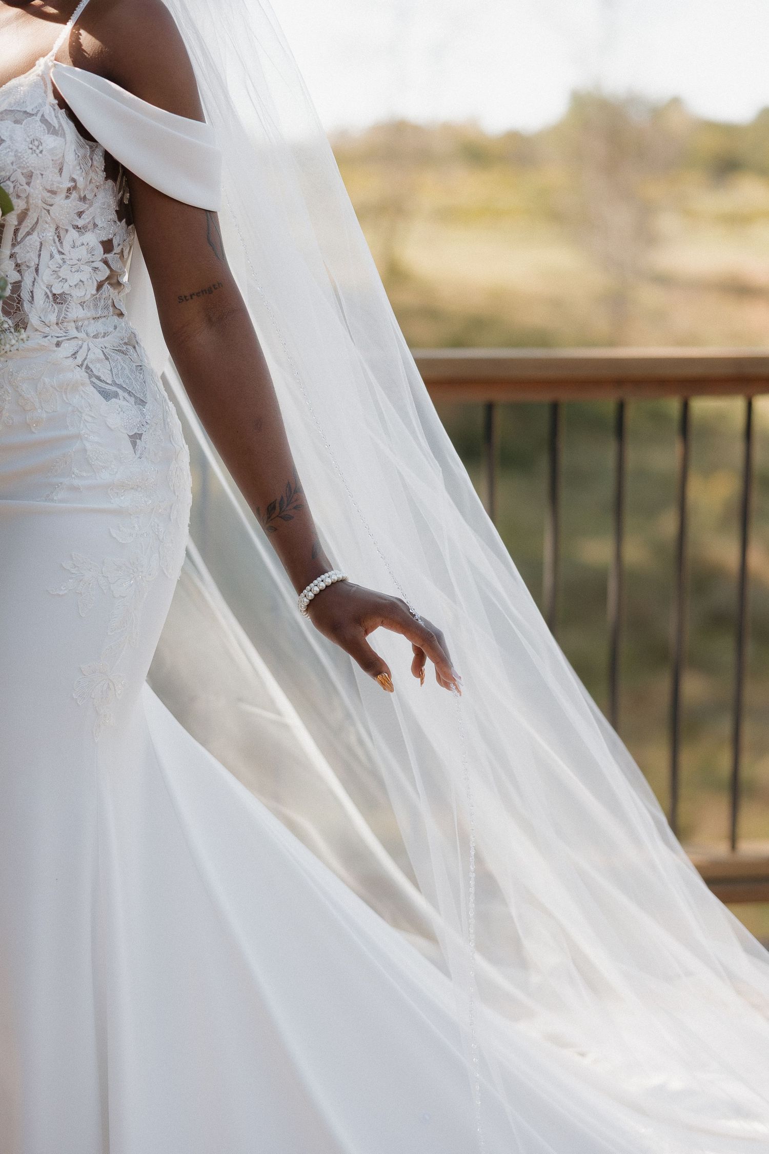 Close-up detail of delicate lace wedding dress and flowing veil.