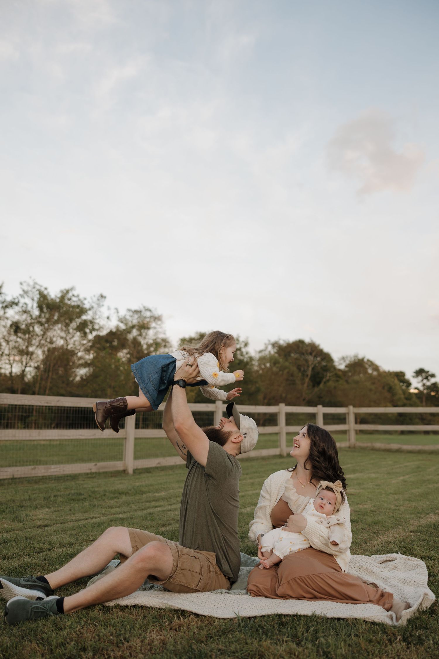 Couple laying on blanket in grassy field sharing intimate moments at sunset.