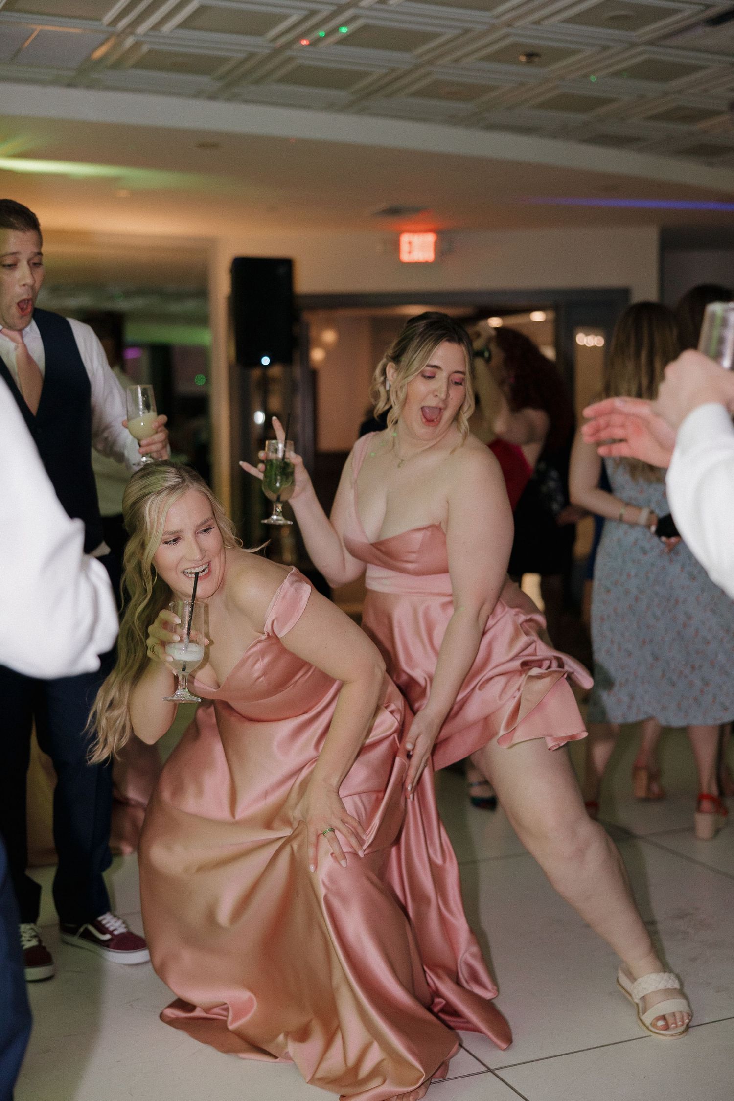 Wedding reception guests dancing and celebrating in pink dresses.