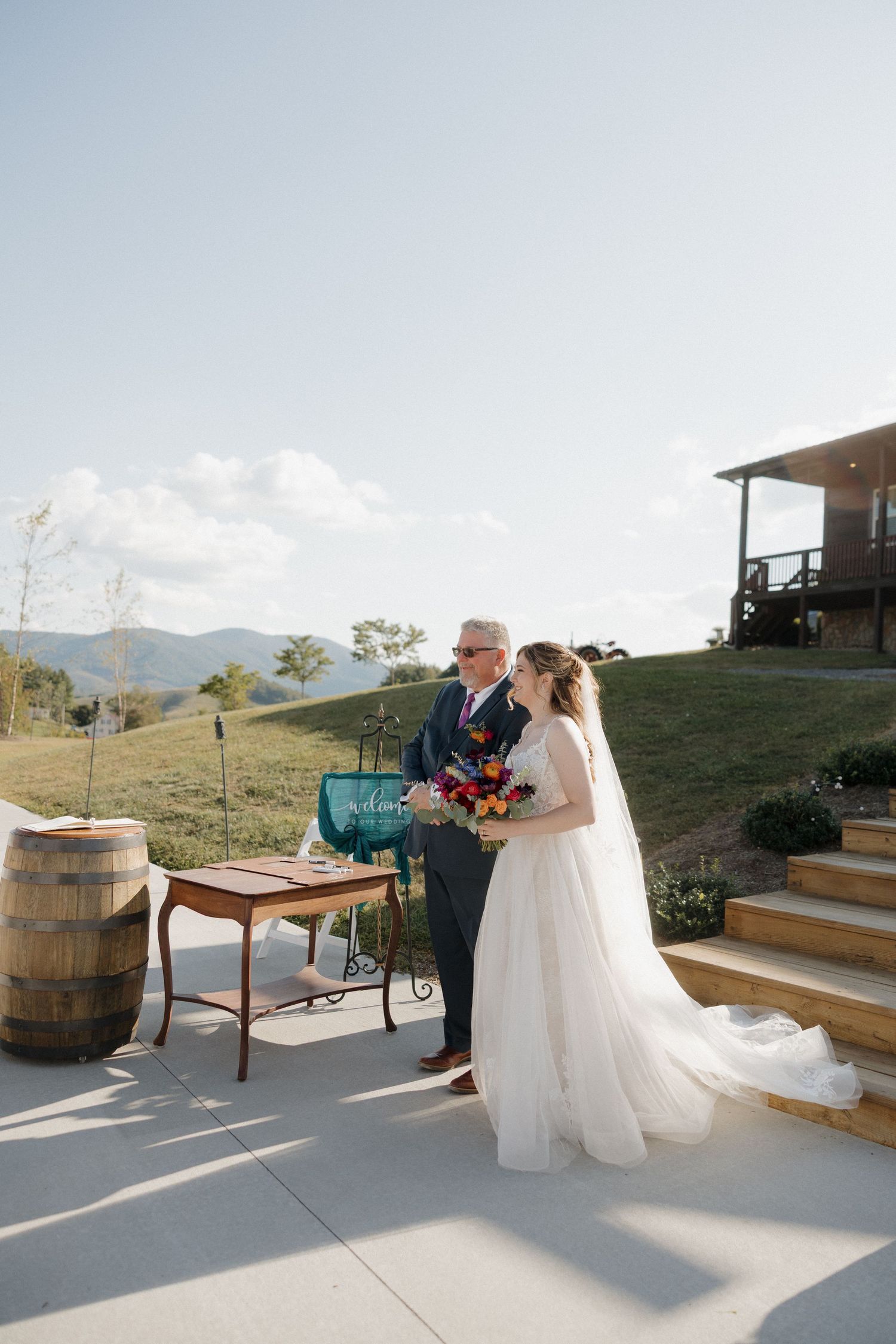 Outdoor wedding venue with wooden barrels and mountain views during golden hour.