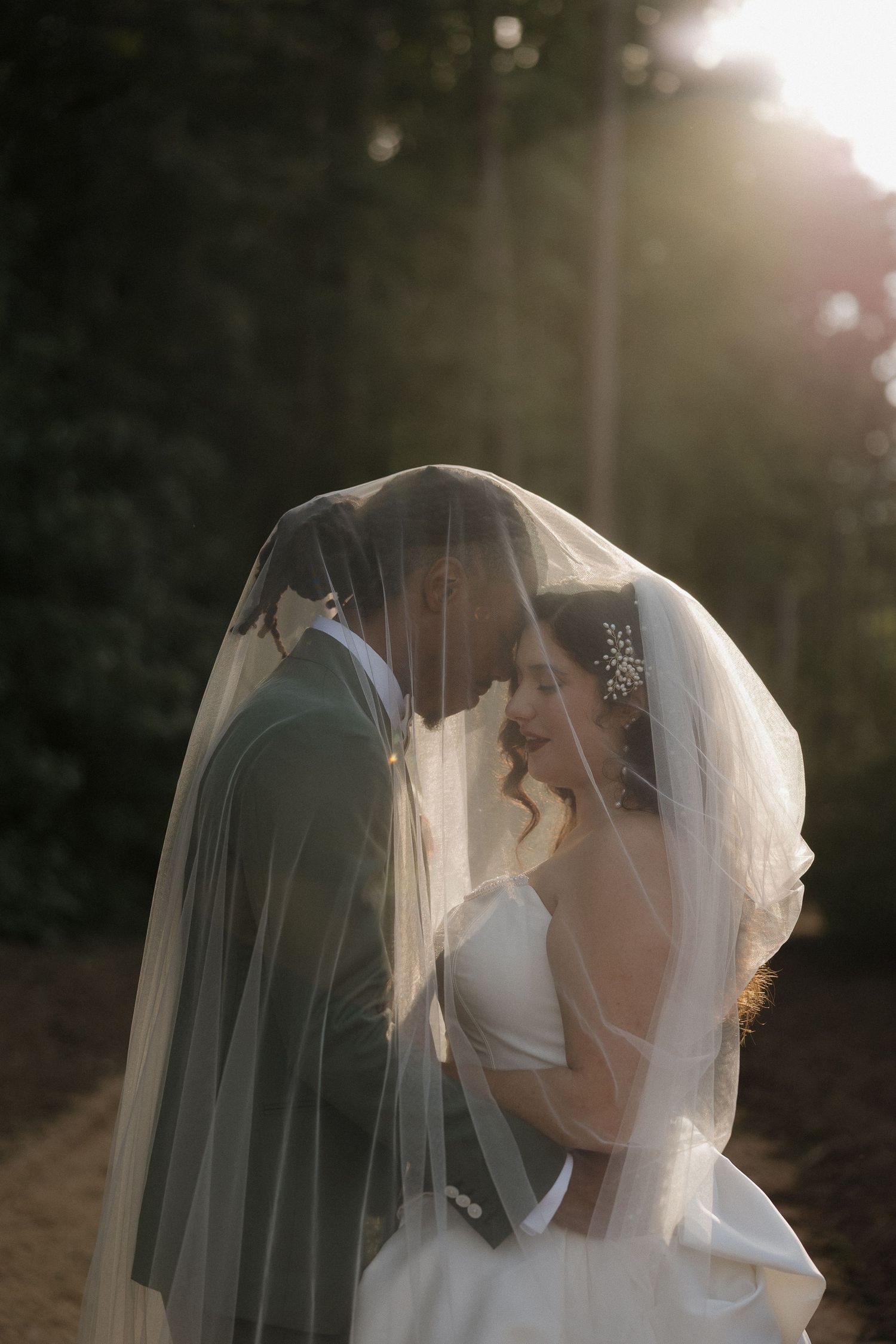 An intimate wedding moment captured through a flowing veil at golden hour.