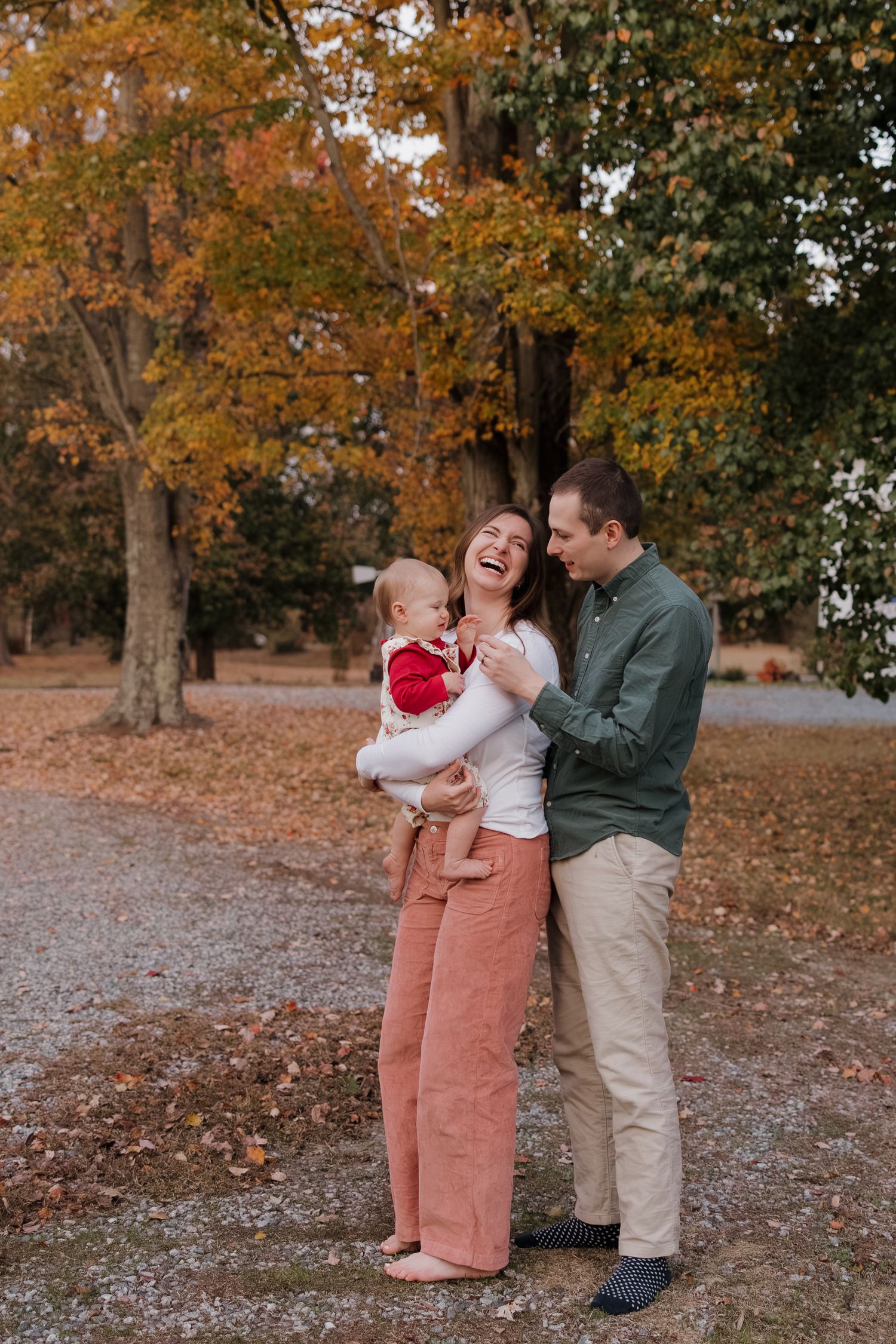 Family shares tender moments together during autumn photo session in park with fallen leaves.