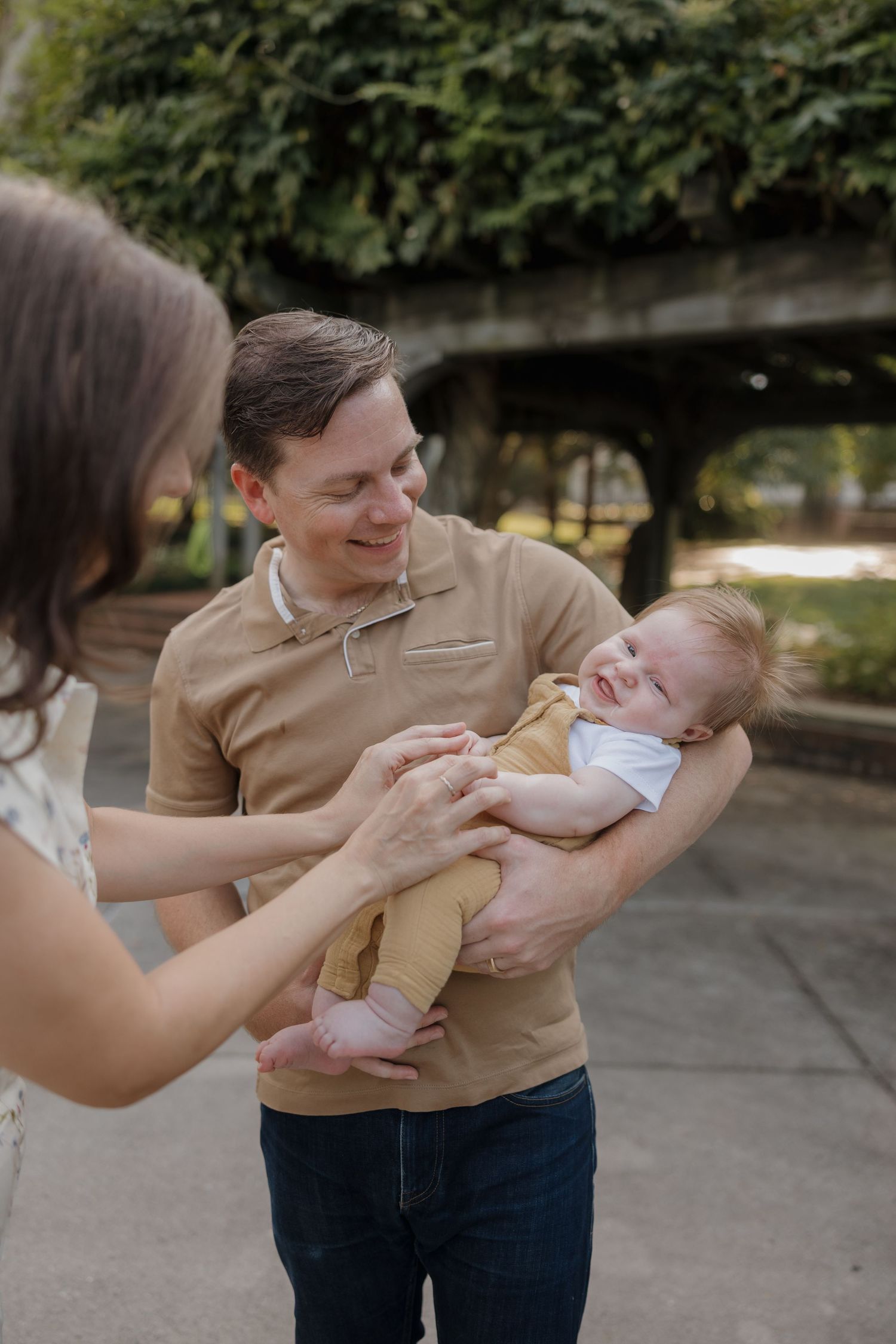 A parent in a tan sweater lovingly holds and plays with a baby outdoors in a sequence of candid moments.