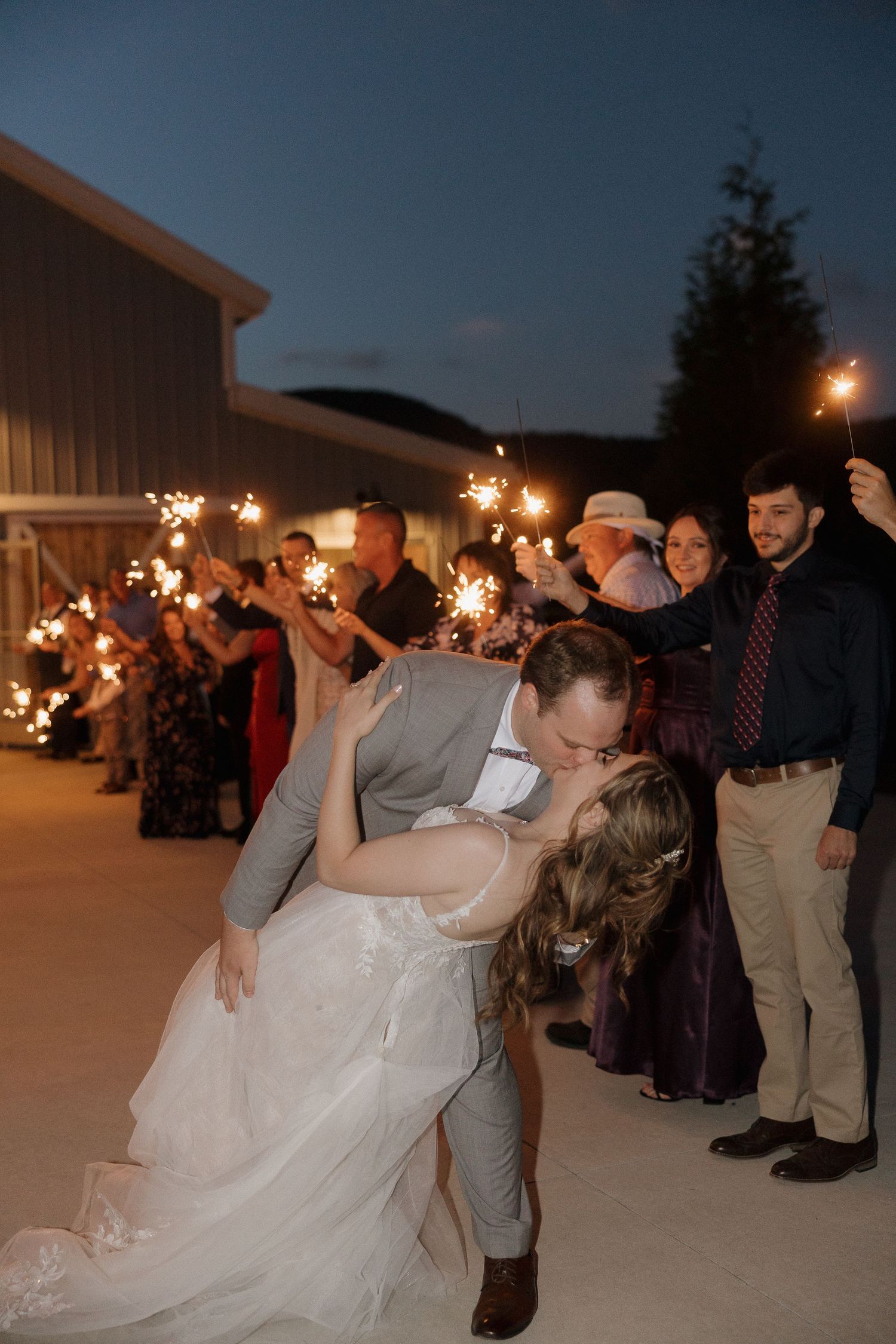 Wedding sparkler exit at night with guests creating a magical light tunnel.