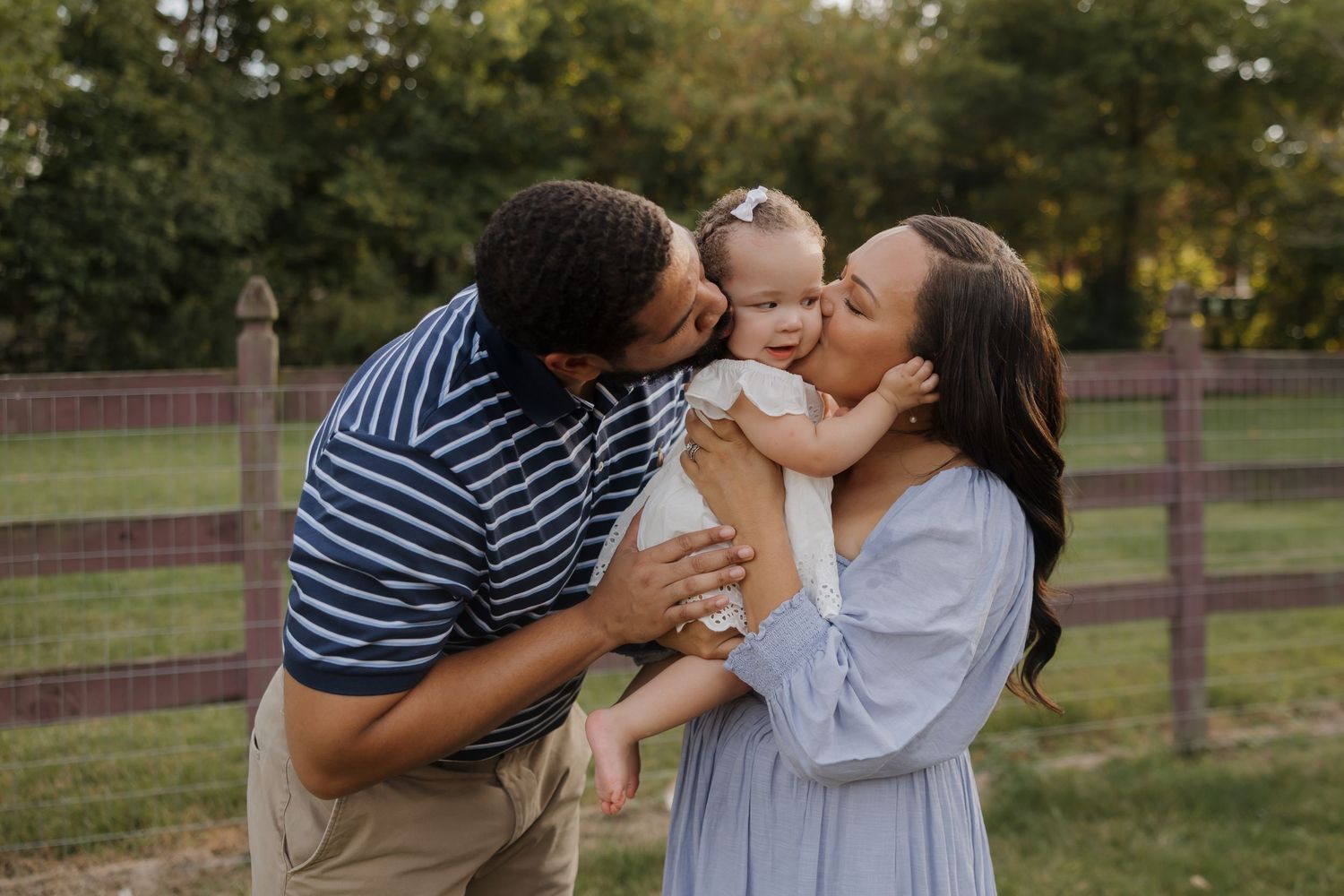 A family shares tender moments together in a park setting during an outdoor photo session.