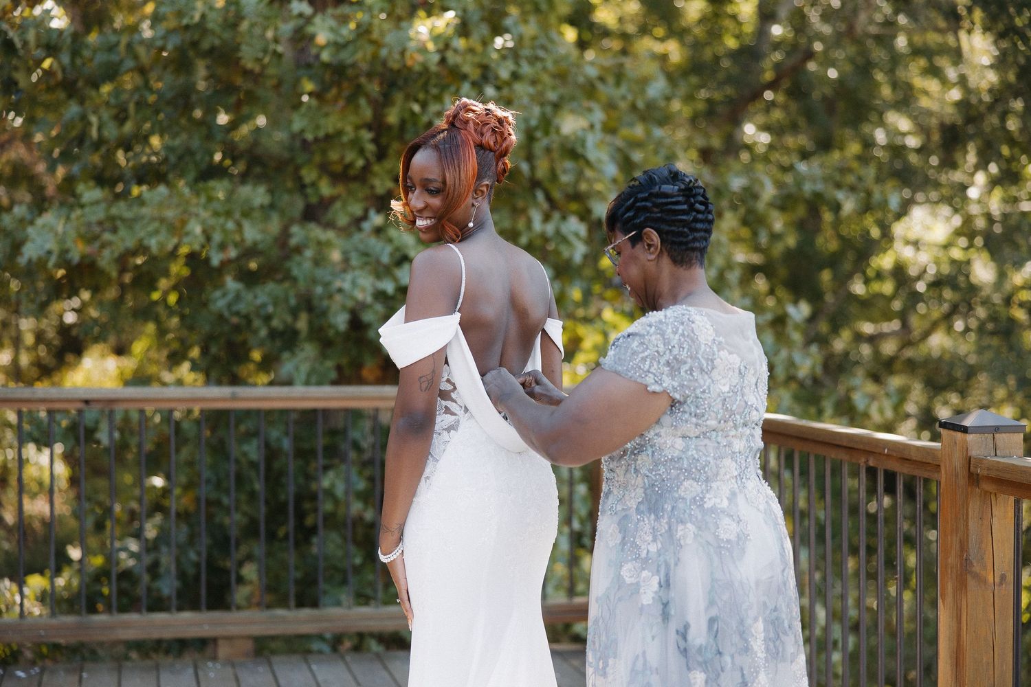 Couple in white dresses walking along wooden deck during sunset.