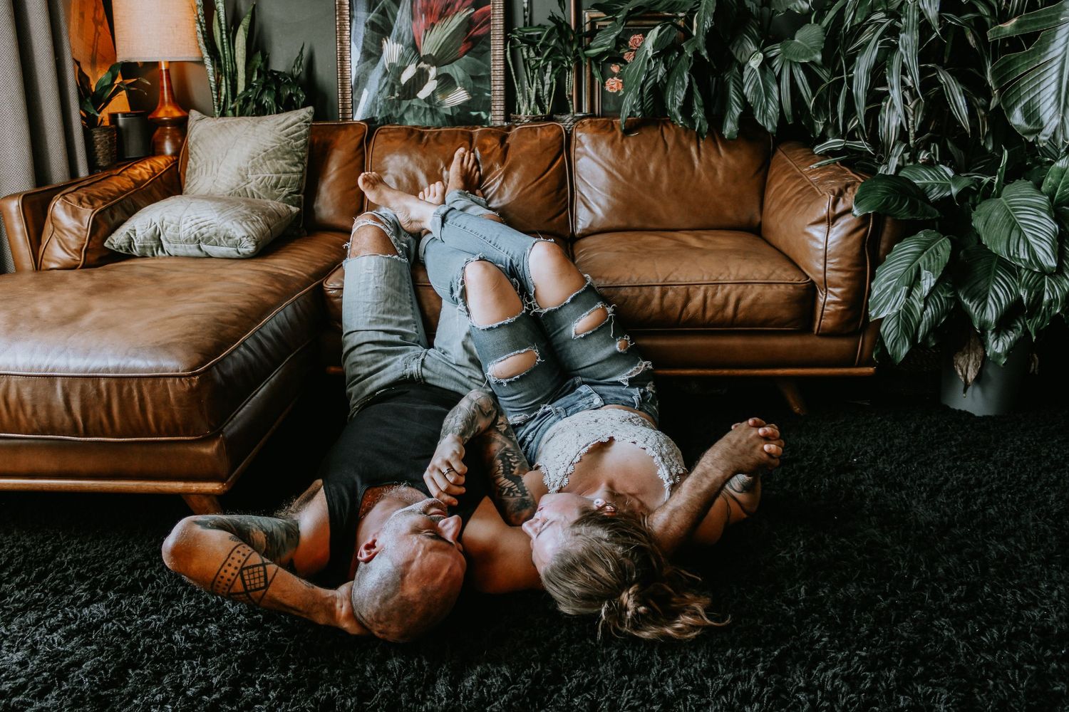 Couple relaxing together on a brown leather couch in a cozy living room setting.