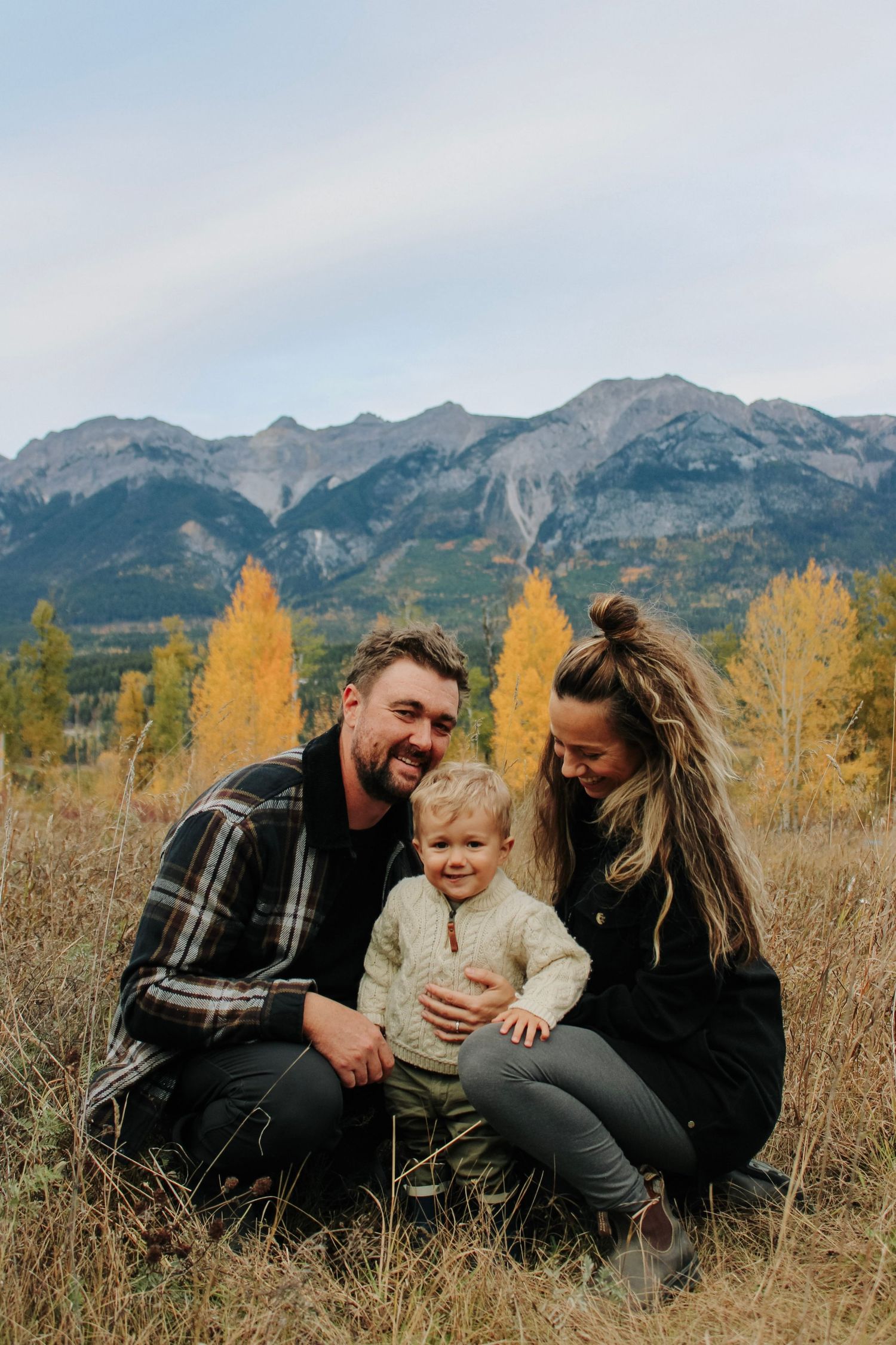 Family enjoying playful moments together in mountain meadow during fall.