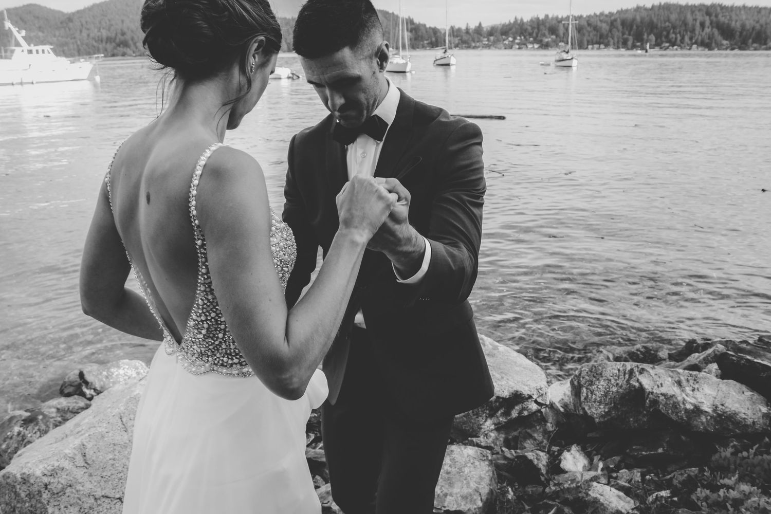 Couple sharing a romantic dance moment by the waterfront with boats in the background.
