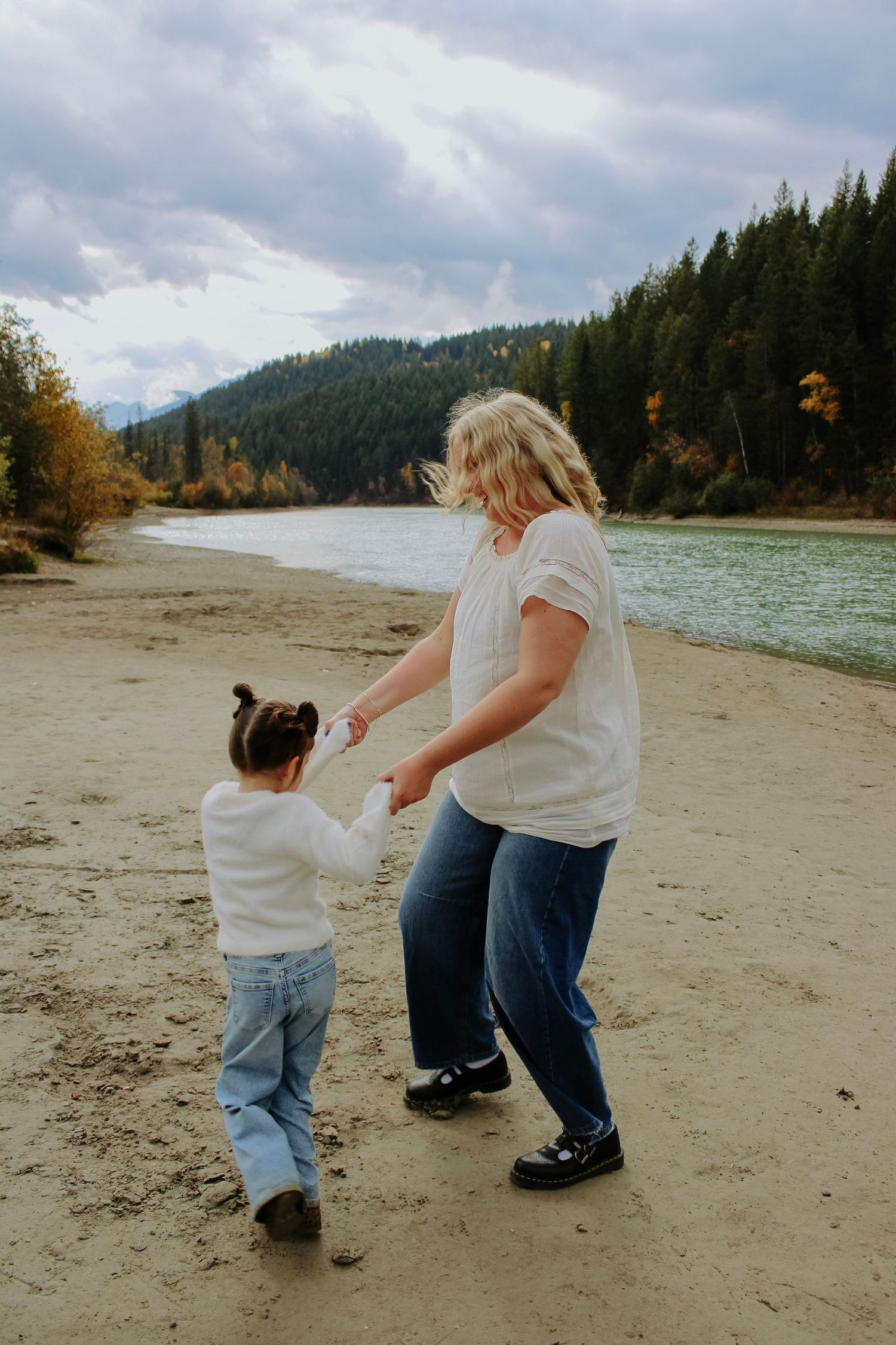 A series of photos shows a parent and child walking together along a scenic beach with mountains and forest in the background.