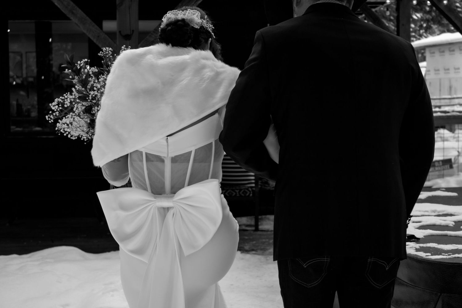 Black and white winter wedding photos showing romantic moments between newlyweds in snowy outdoor setting.