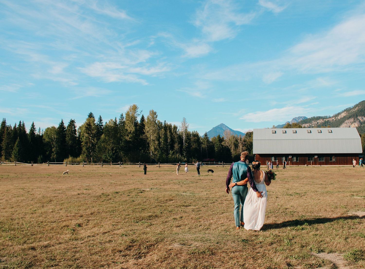 Panoramic view of mountain landscape with couple in distance on their wedding day.
