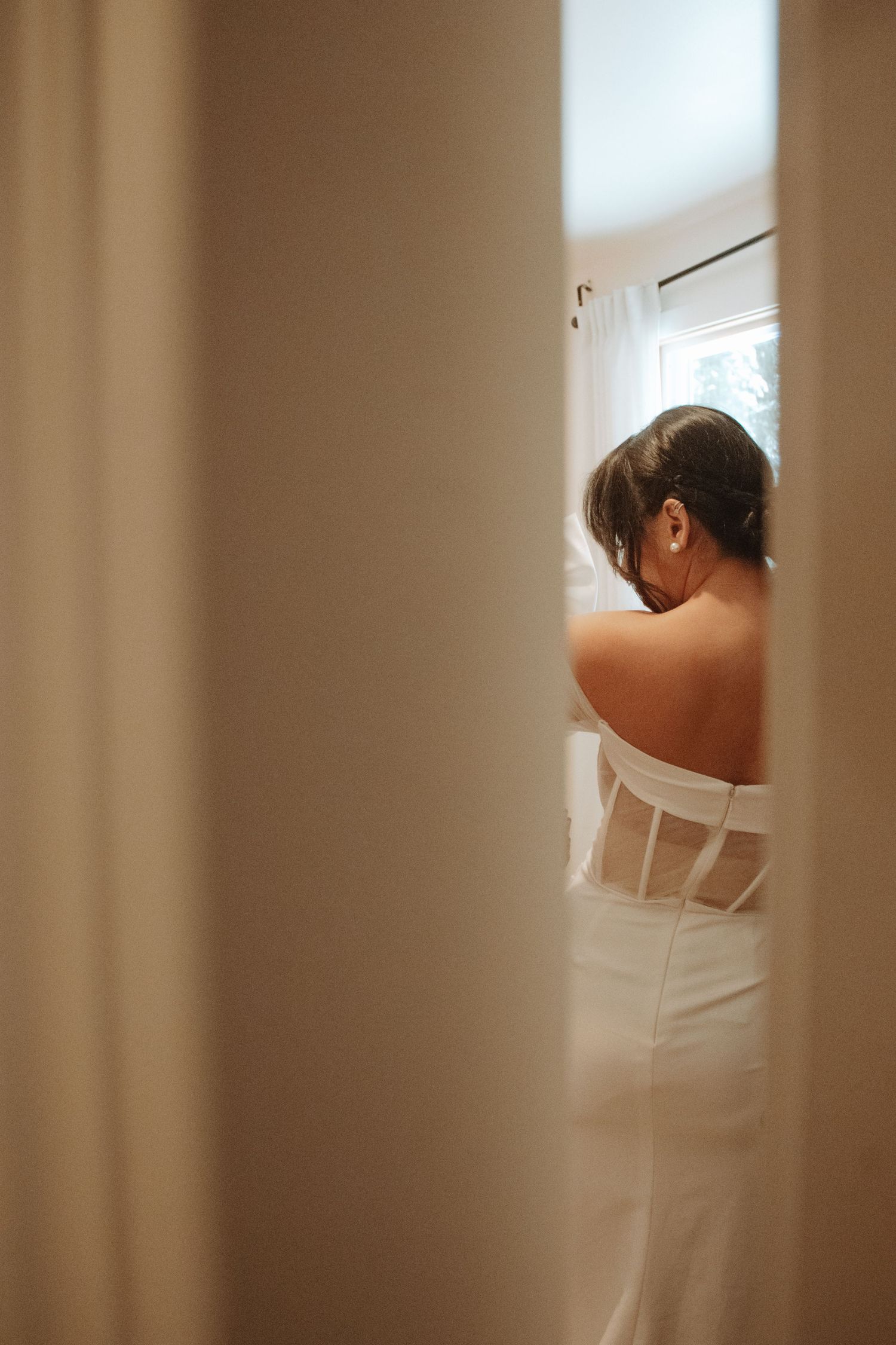 A series of soft, minimalist photographs showing a person in a white dress against neutral beige walls.