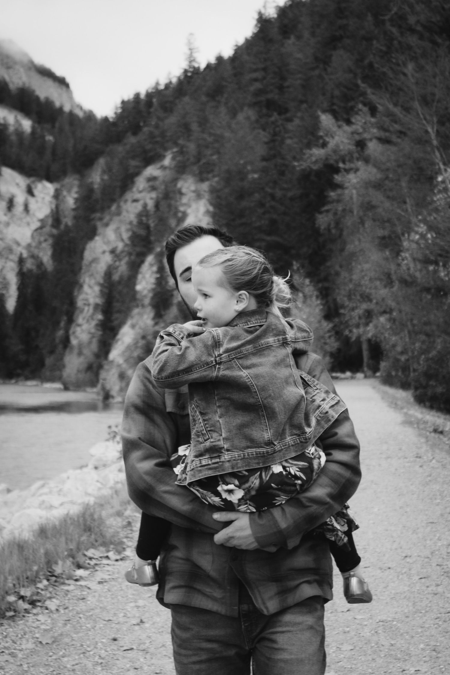 Black and white portrait on a mountain trail with rocky cliffs in background.