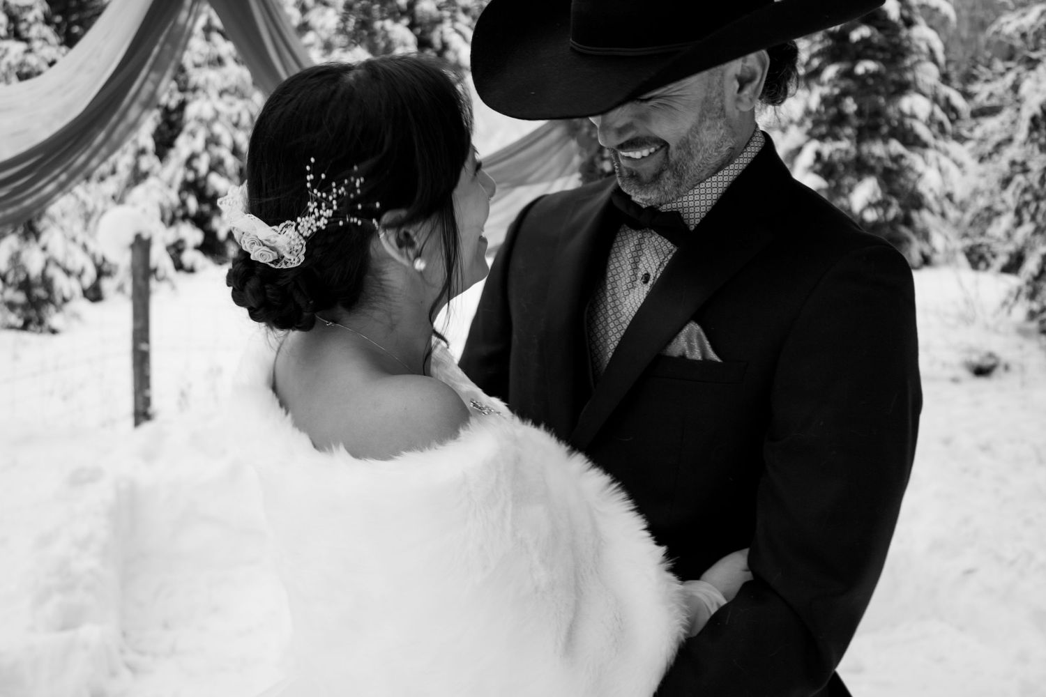 Romantic black and white winter wedding portraits featuring couple embracing in snowy outdoor setting.