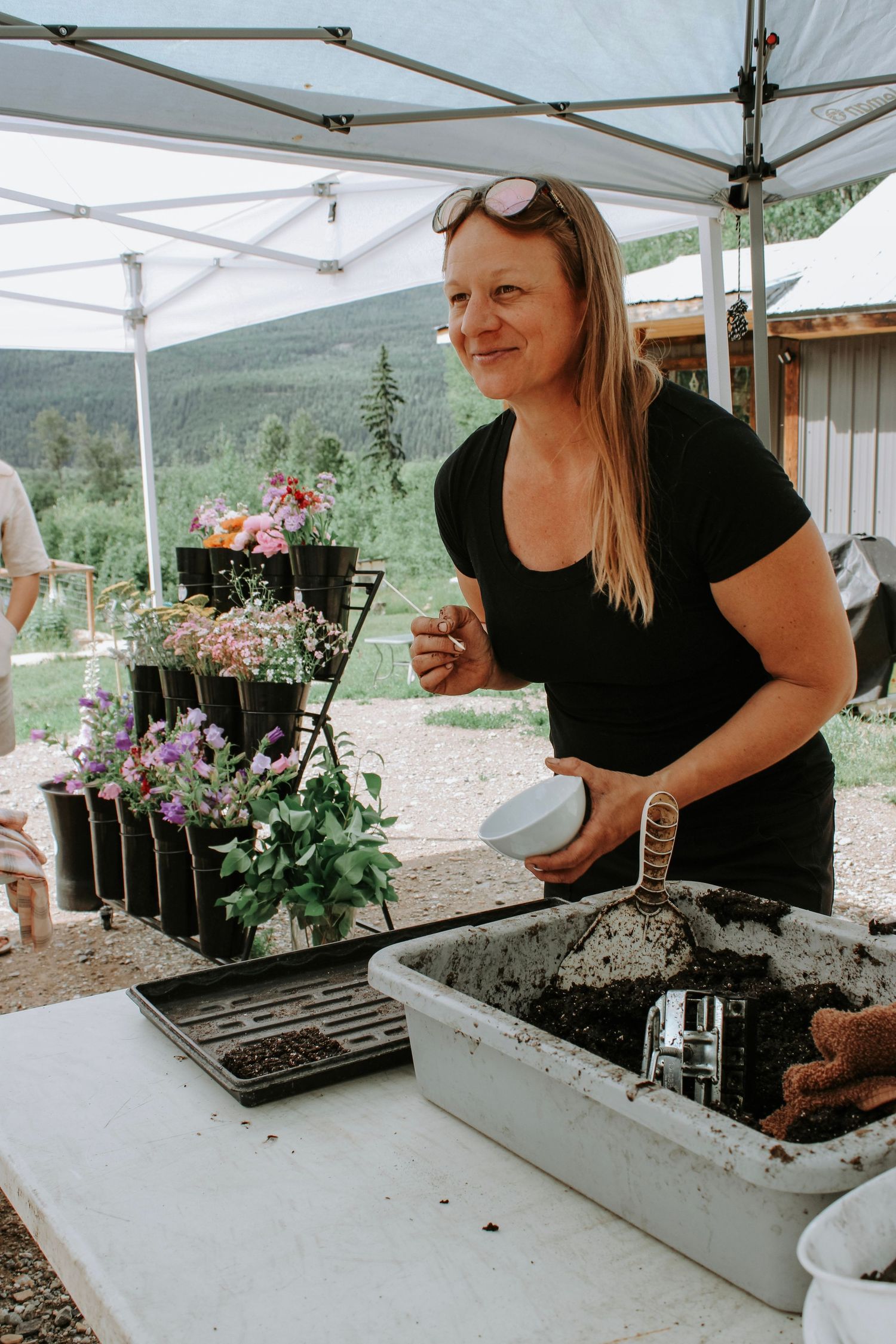 Vendor working at an outdoor market stall with floral displays and planter boxes.