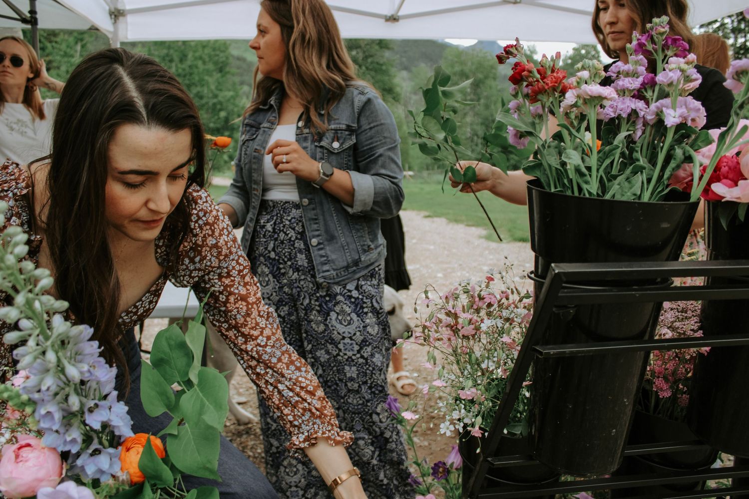 People browsing floral arrangements at an outdoor market stall.