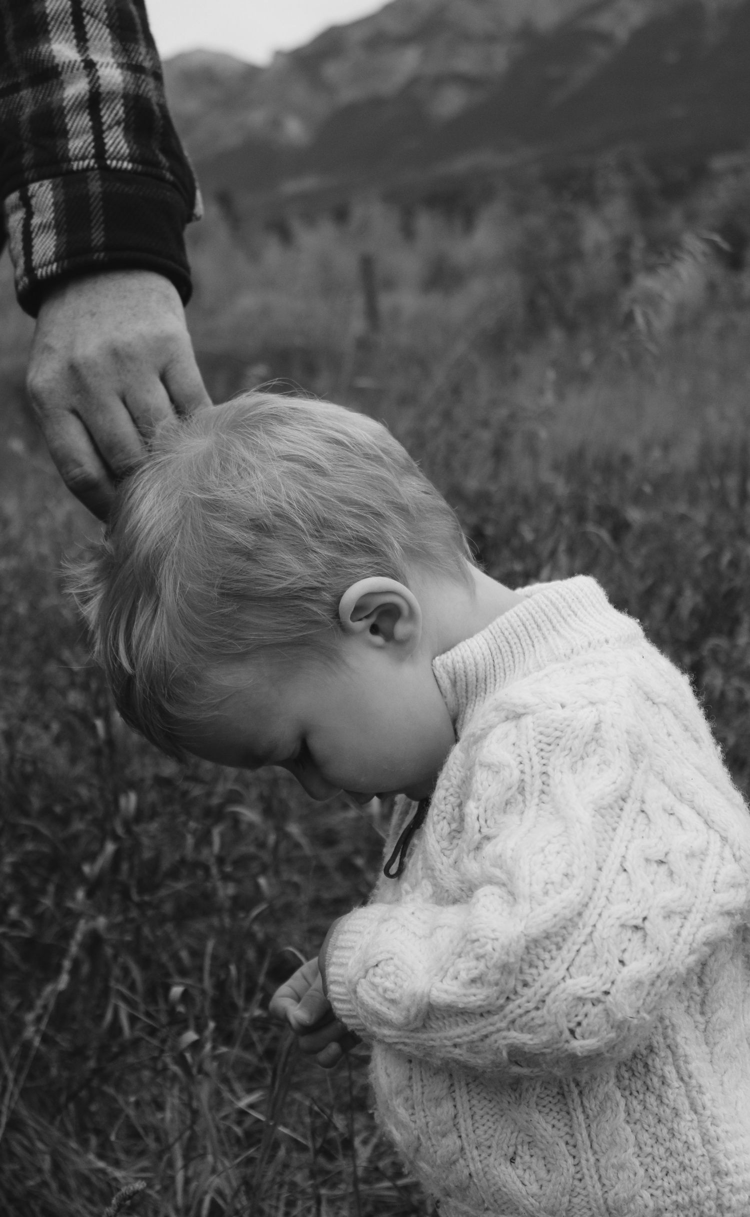 Black and white close-up showing a cozy white knit sweater against mountain scenery.