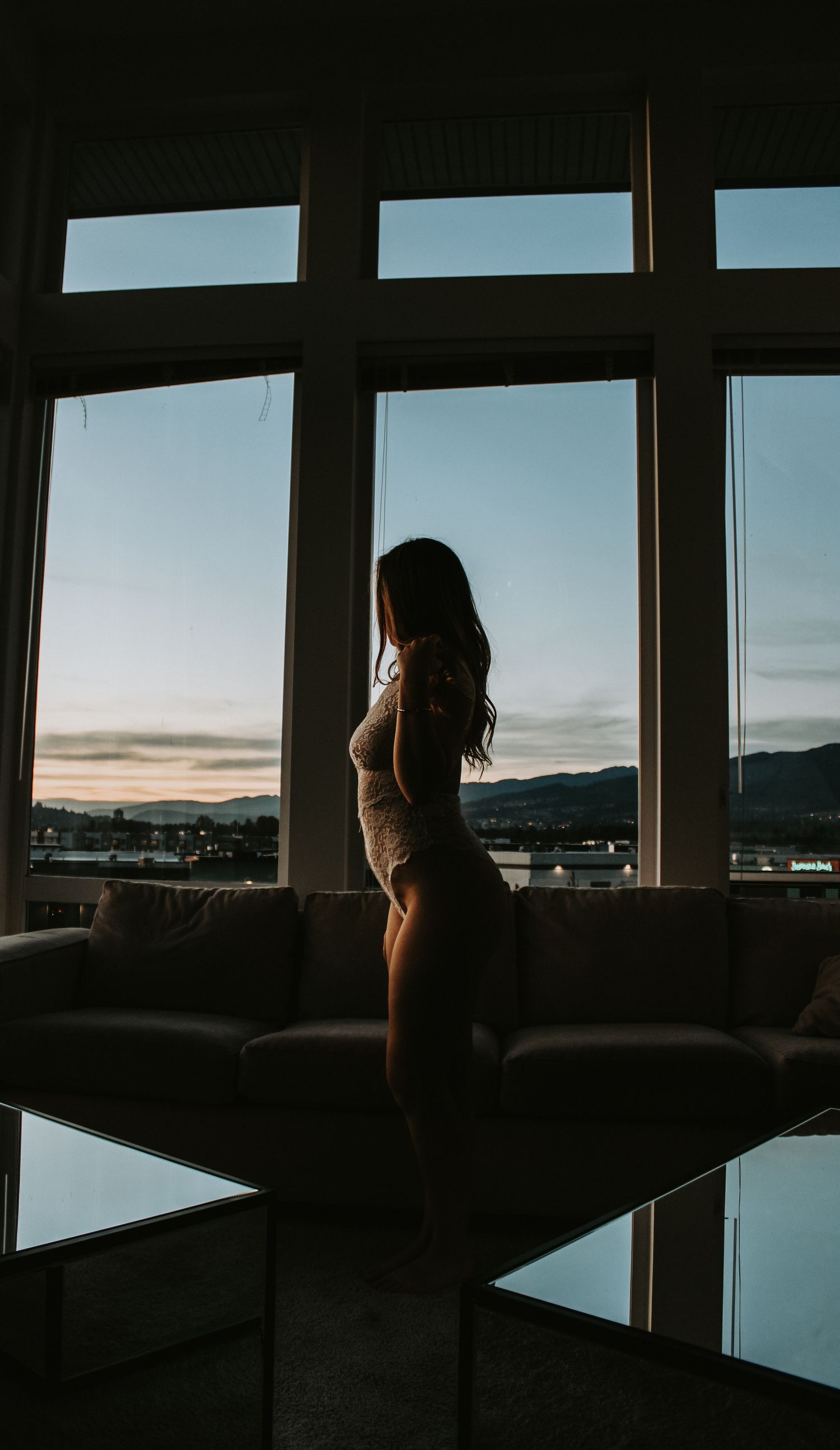 Silhouette against large windows overlooking mountain landscape at sunset.