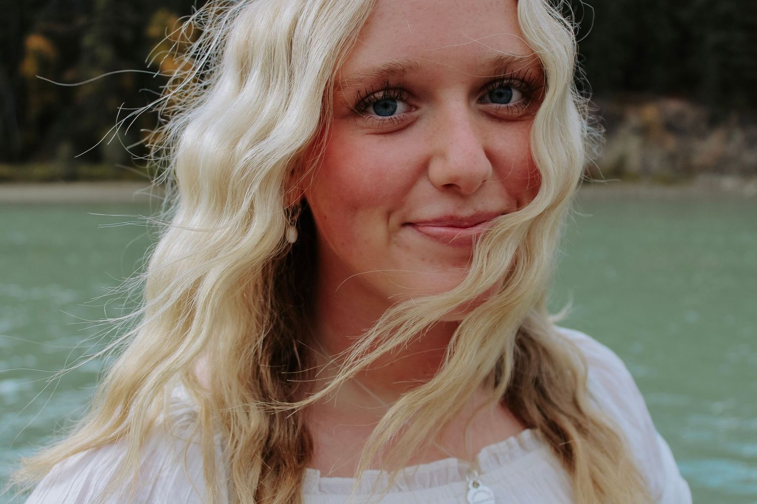 Portrait sequence near turquoise water with mountains and forest in background.
