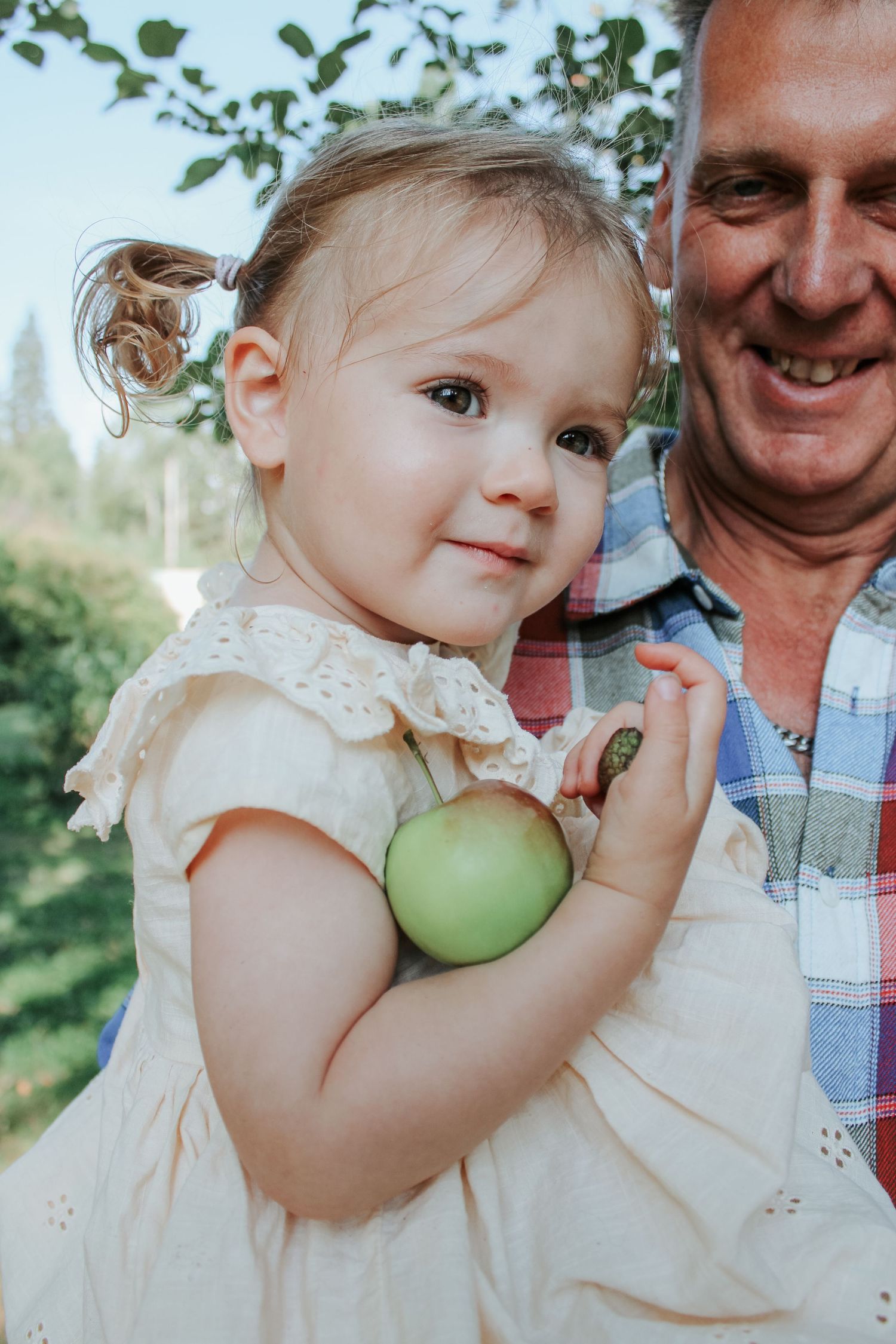 A sweet moment with a baby holding a green apple during an outdoor family photoshoot.