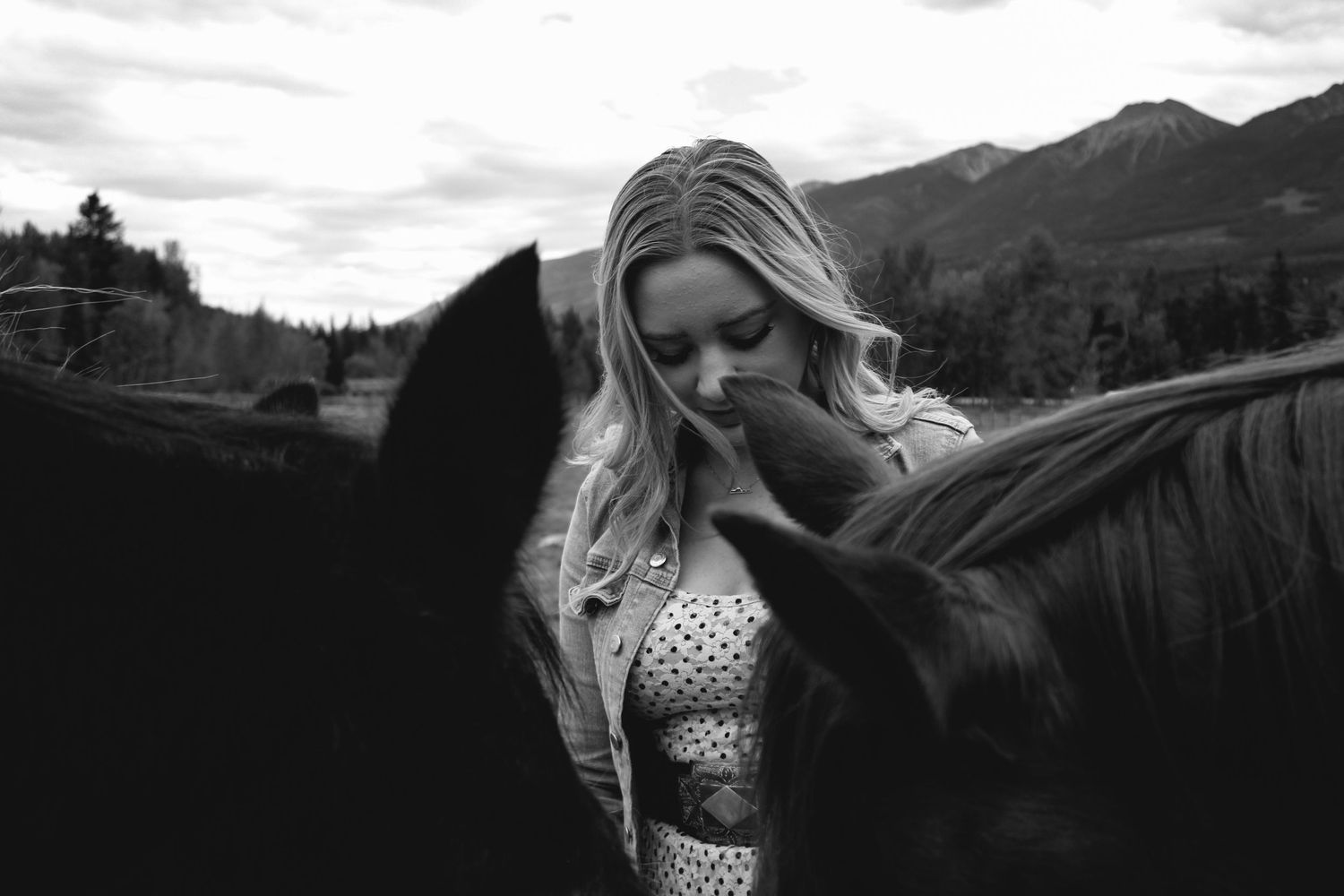 Black and white artistic portrait in mountain landscape with dramatic clouds.