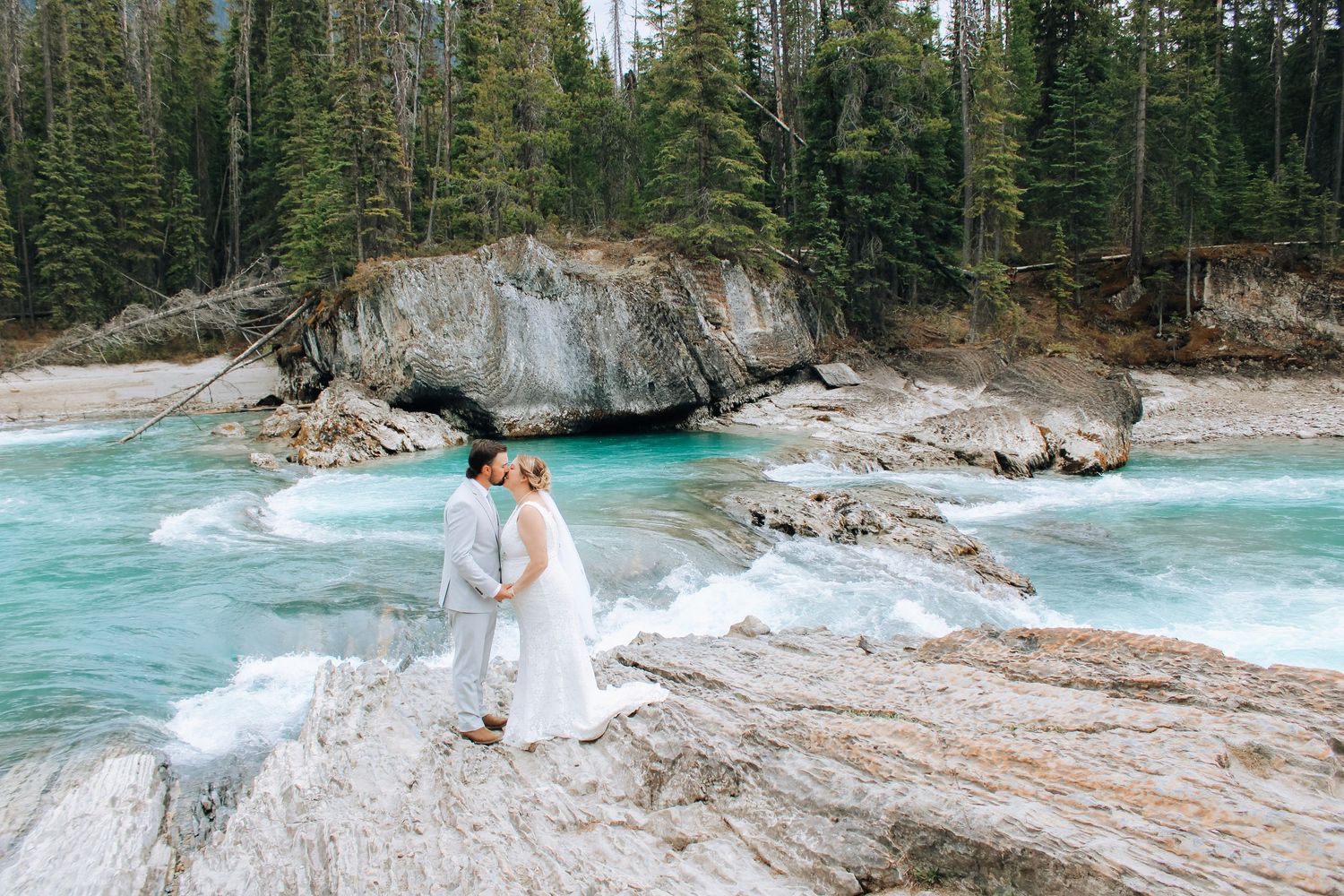 A scenic river winding through dense evergreen forest with turquoise water and rocky shoreline.